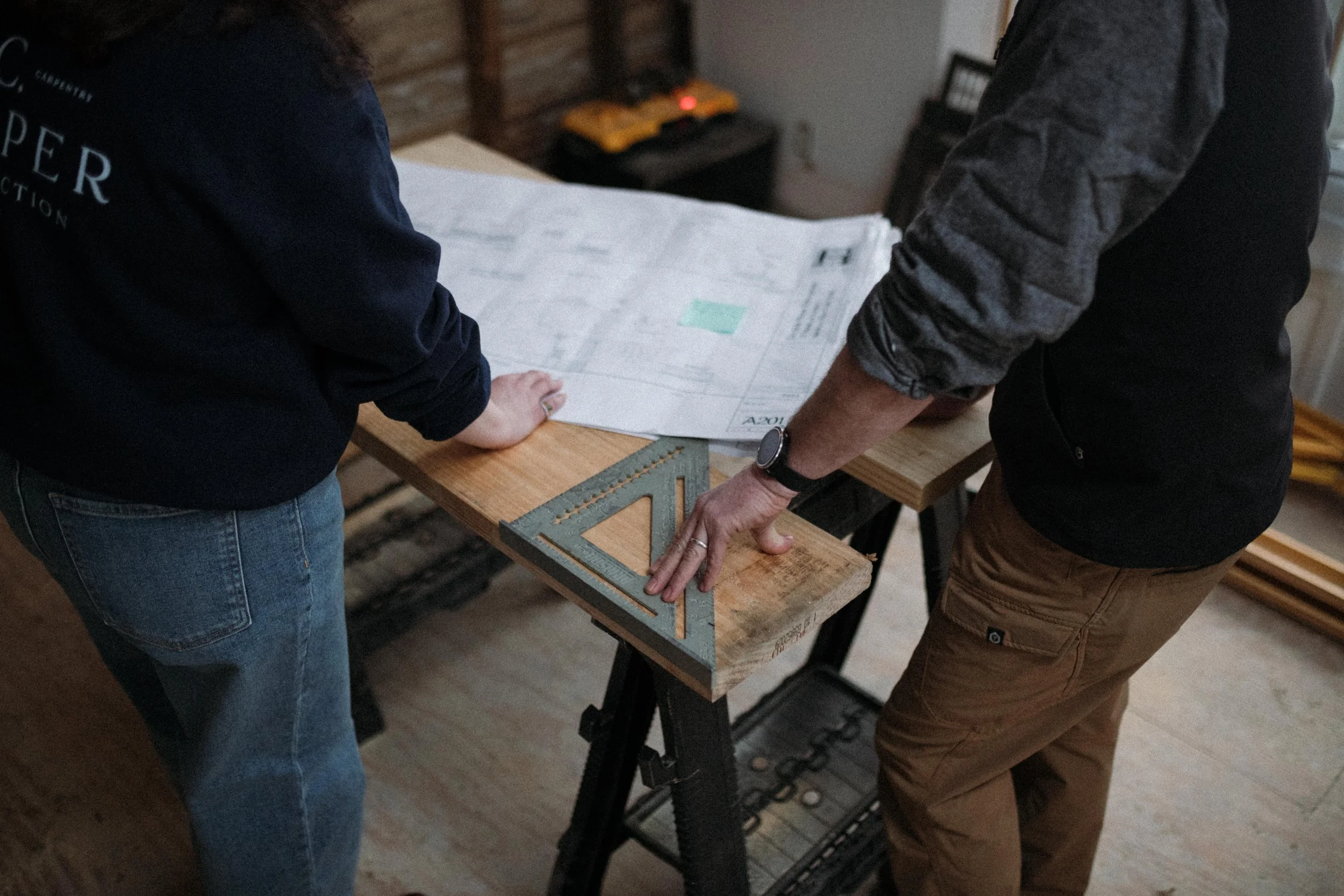 A general contractor in Hamilton, New York review building plans with their carpenter and project manager as they work through a full home renovation in Hamilton, New York.