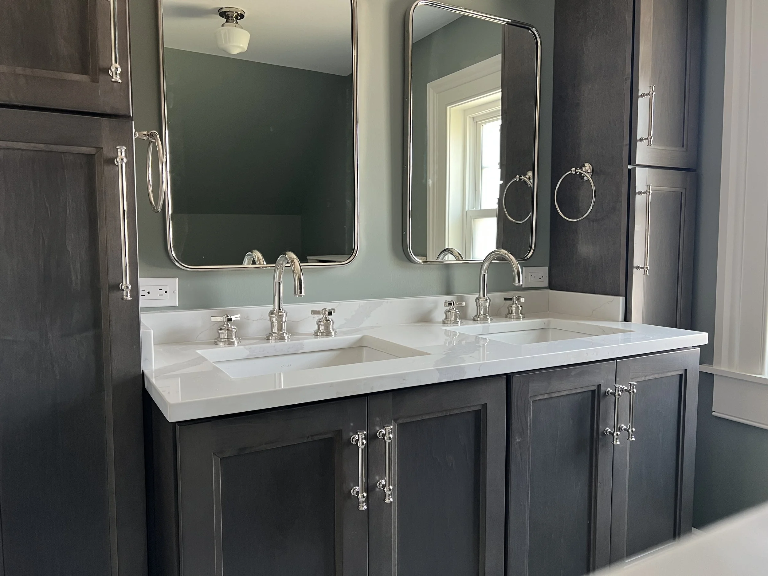 Newly renovated bathroom with dark stained maple cabinets, an off white countertop, polished nickel fixtures and sage green walls. Part of a full home renovation in Hamilton, NY. 