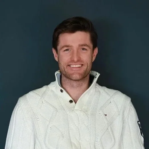 Lächelnder Kunde Josh im weissen Strickpullover vor dunklem Hintergrund