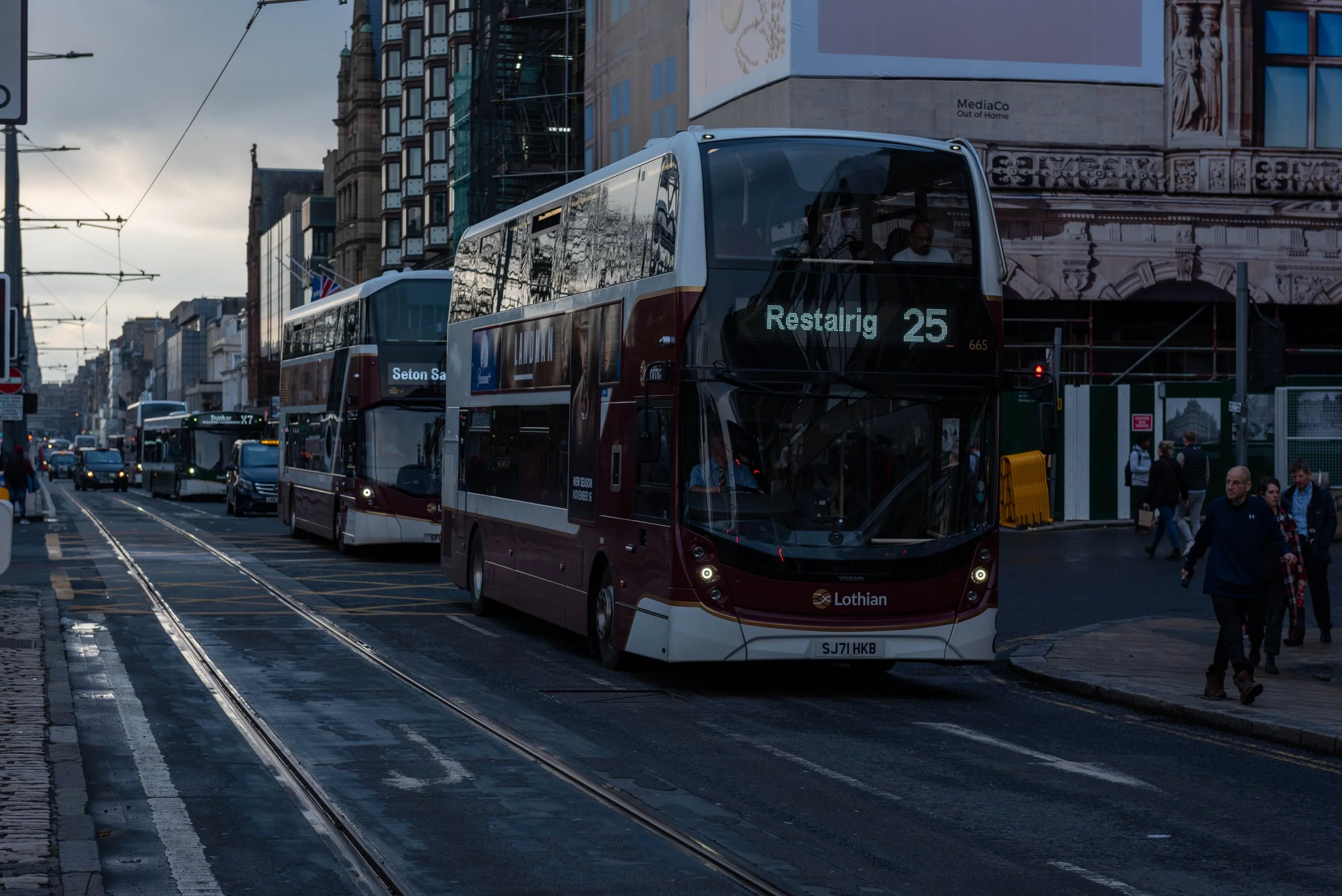 Lothian Buses traveling along Princes Street in central Edinburgh with shops and buildings lining the road