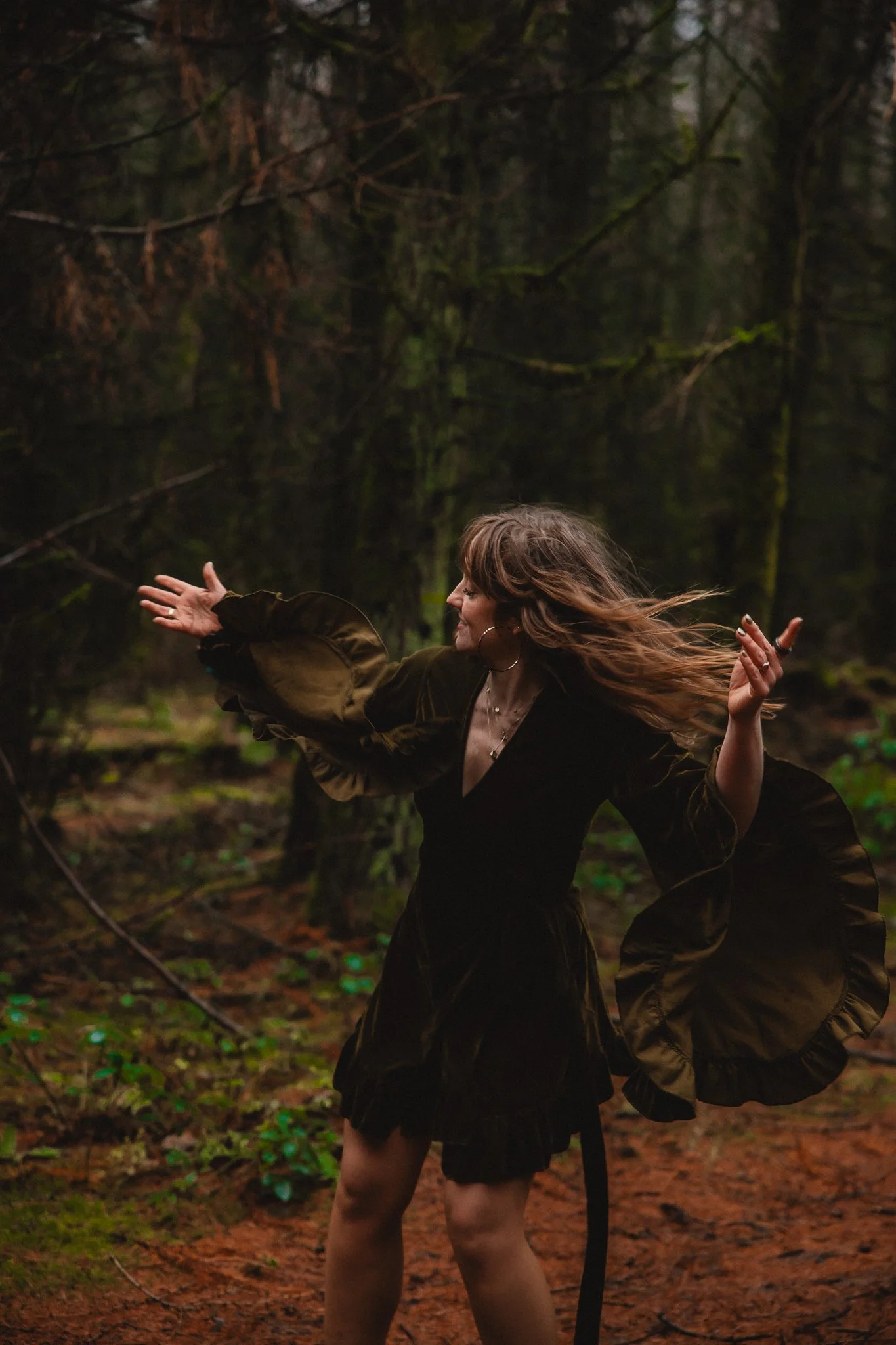 A group of women practice yoga in a studio, with one woman in the foreground doing a pose with hands together above her head, wearing animal print pants and a green top.