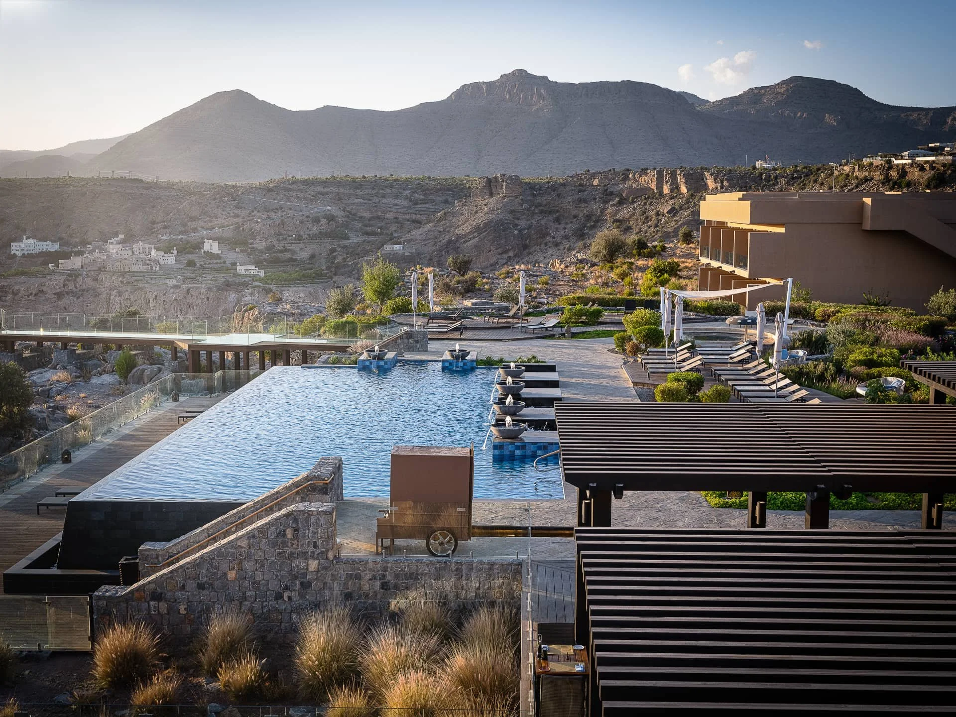 Anantara Al Jabal Akhdar Exterior and Pool View with Cliff and mountains in background 