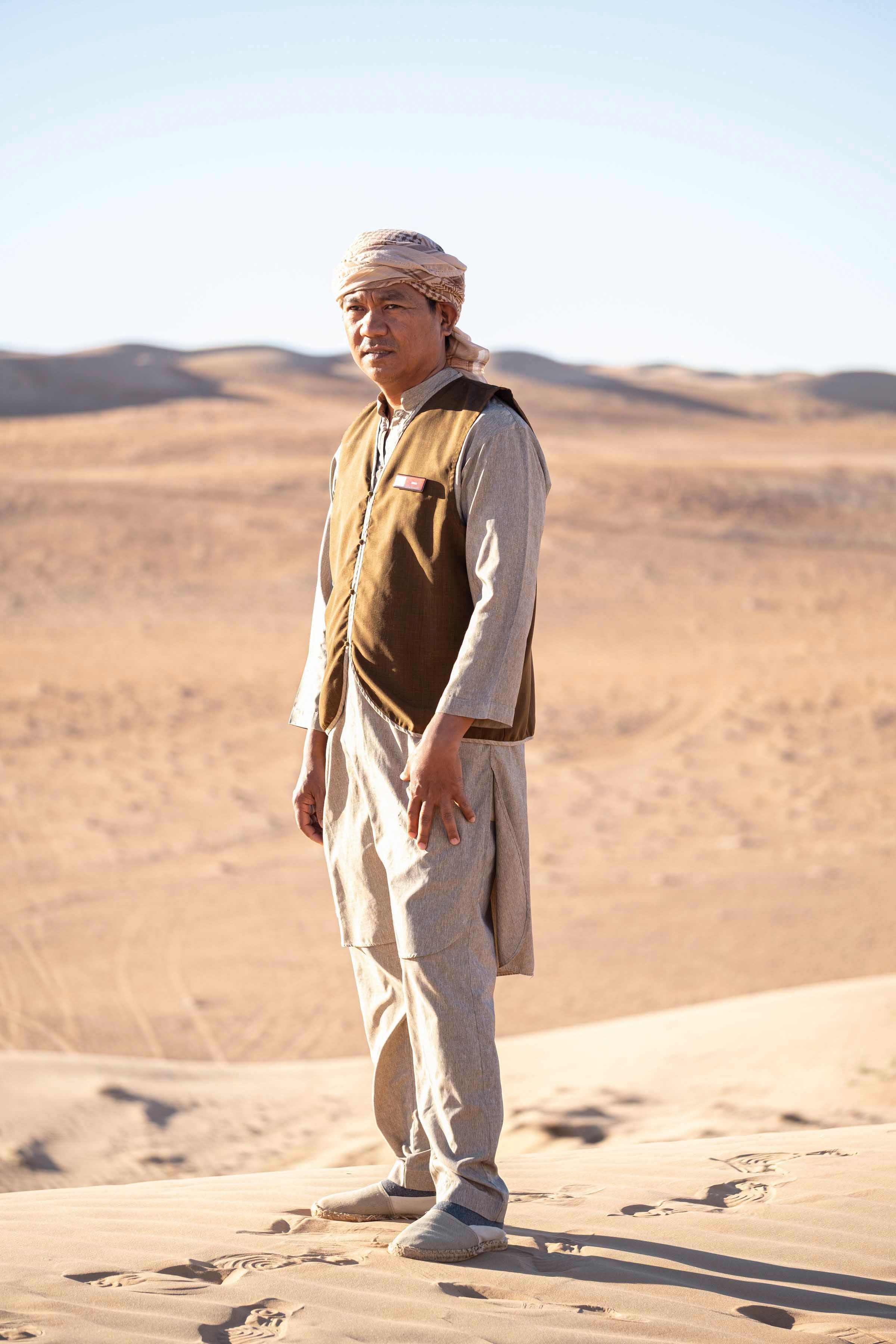 Server of desert camp posing o dunes