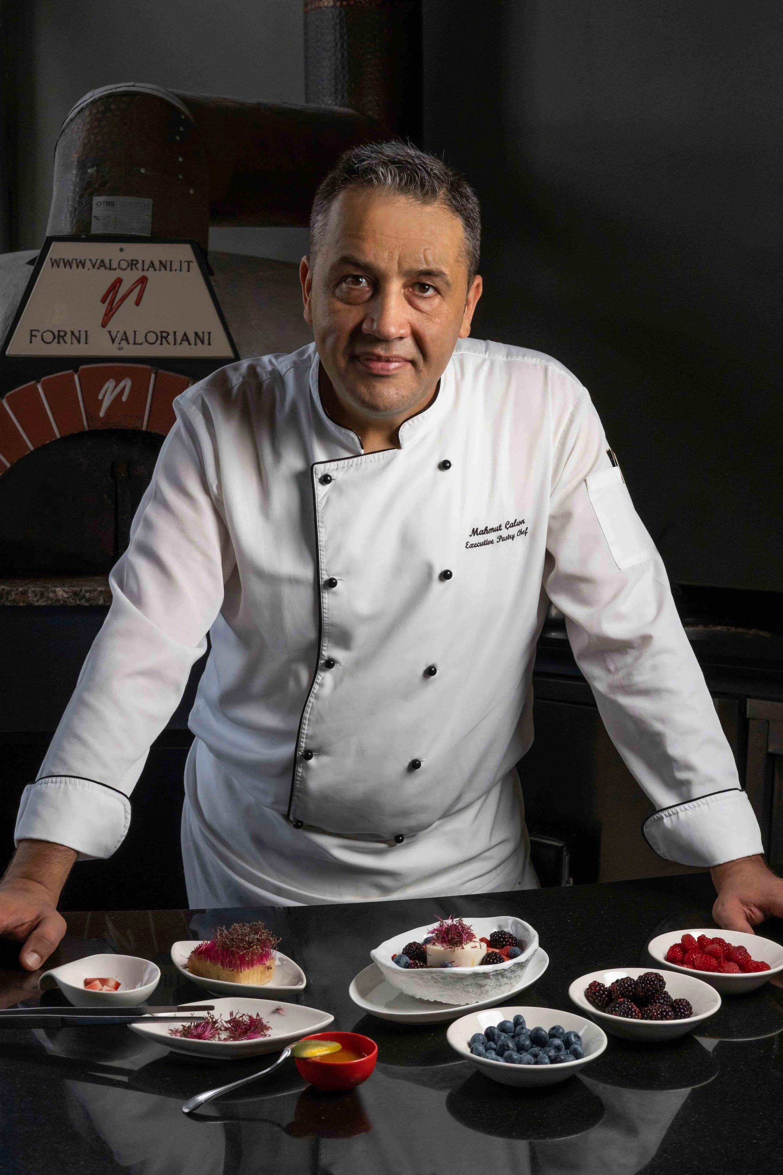 Pastry chef posing in front of counter top