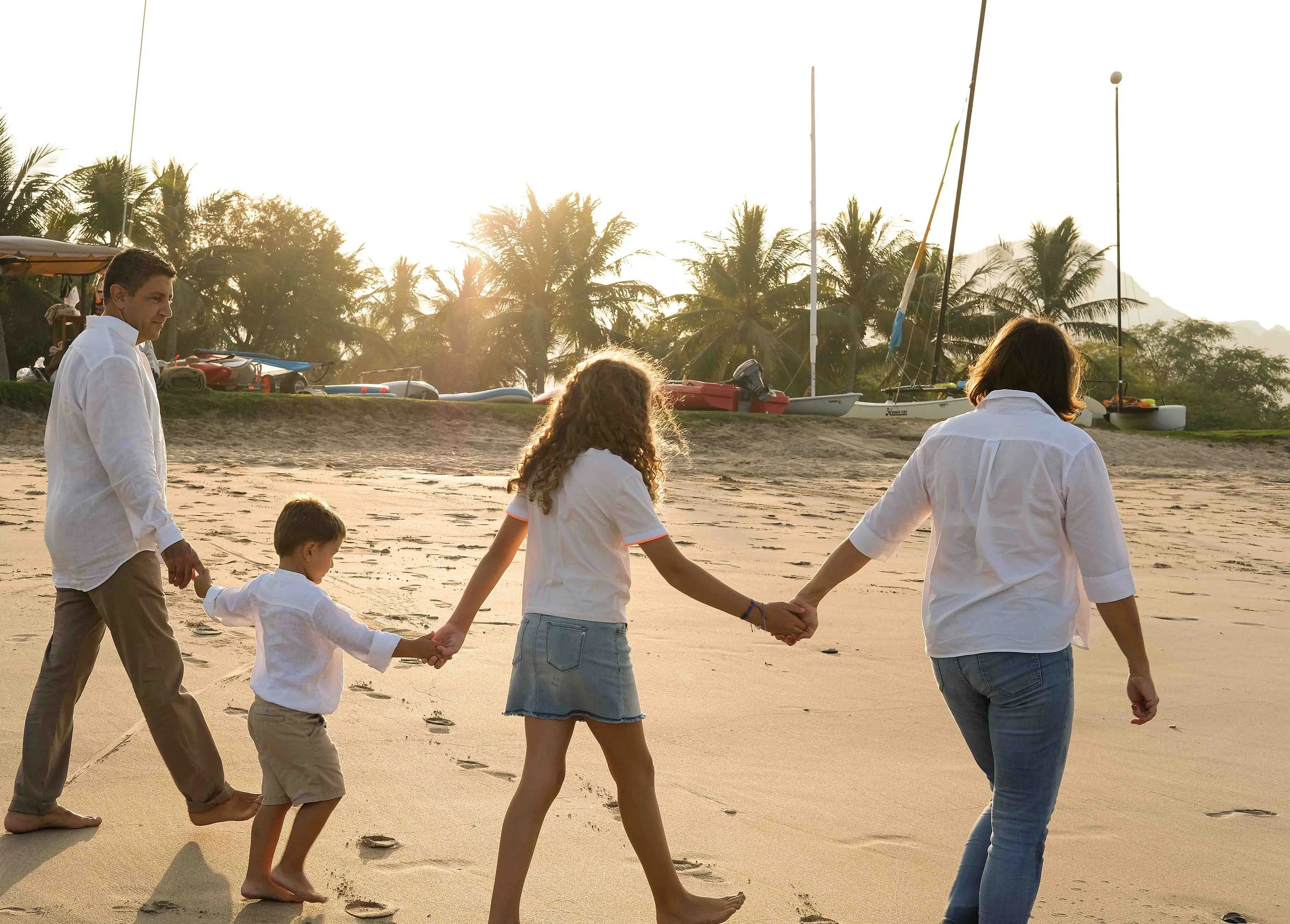 Family of four walking on the beach during sunset 