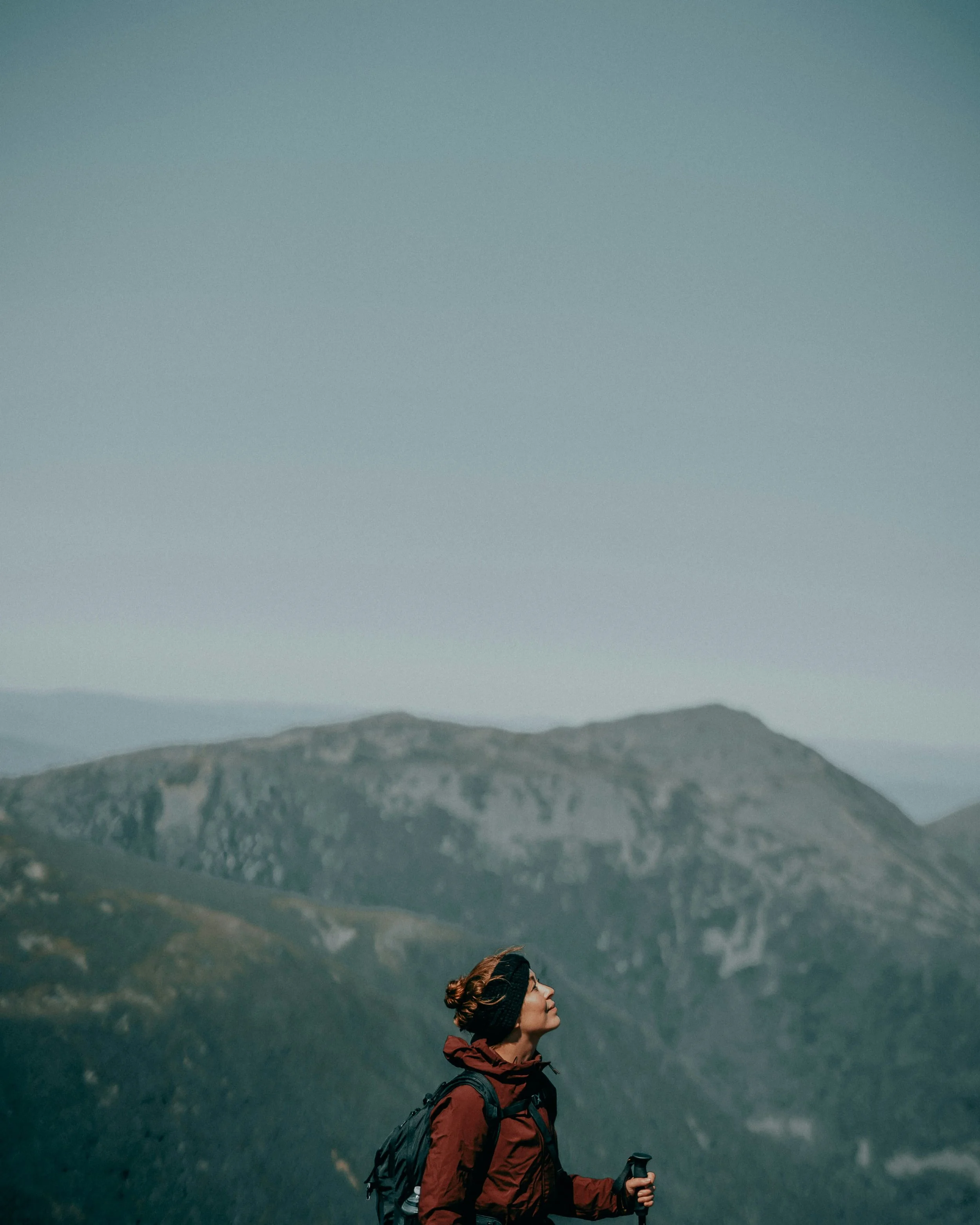 Woman standing outdoors in the mountains, looking upward and practicing grounding and nervous system regulation in nature.