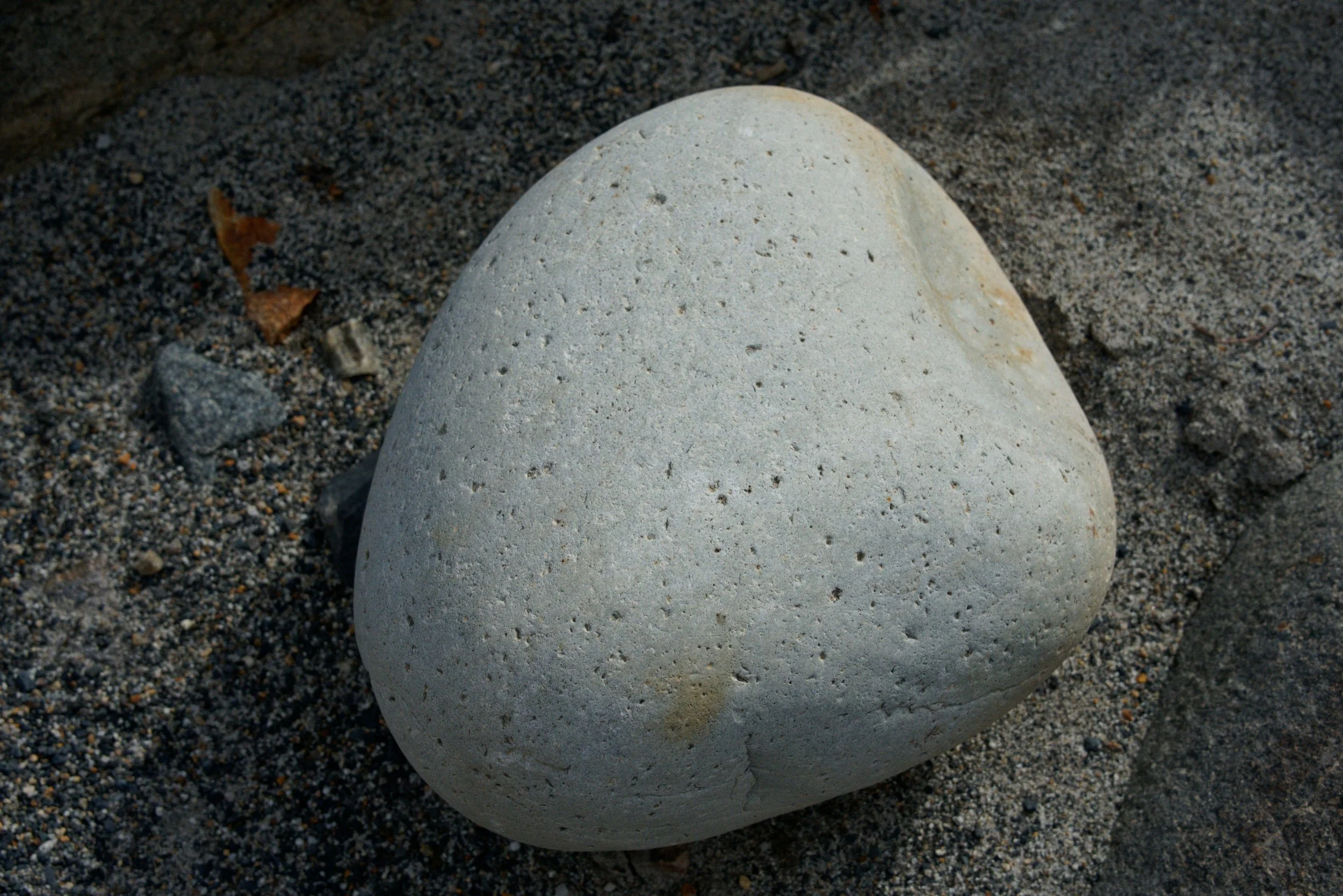 Smooth gray grounding stone on sand, symbolizing safety and steadiness