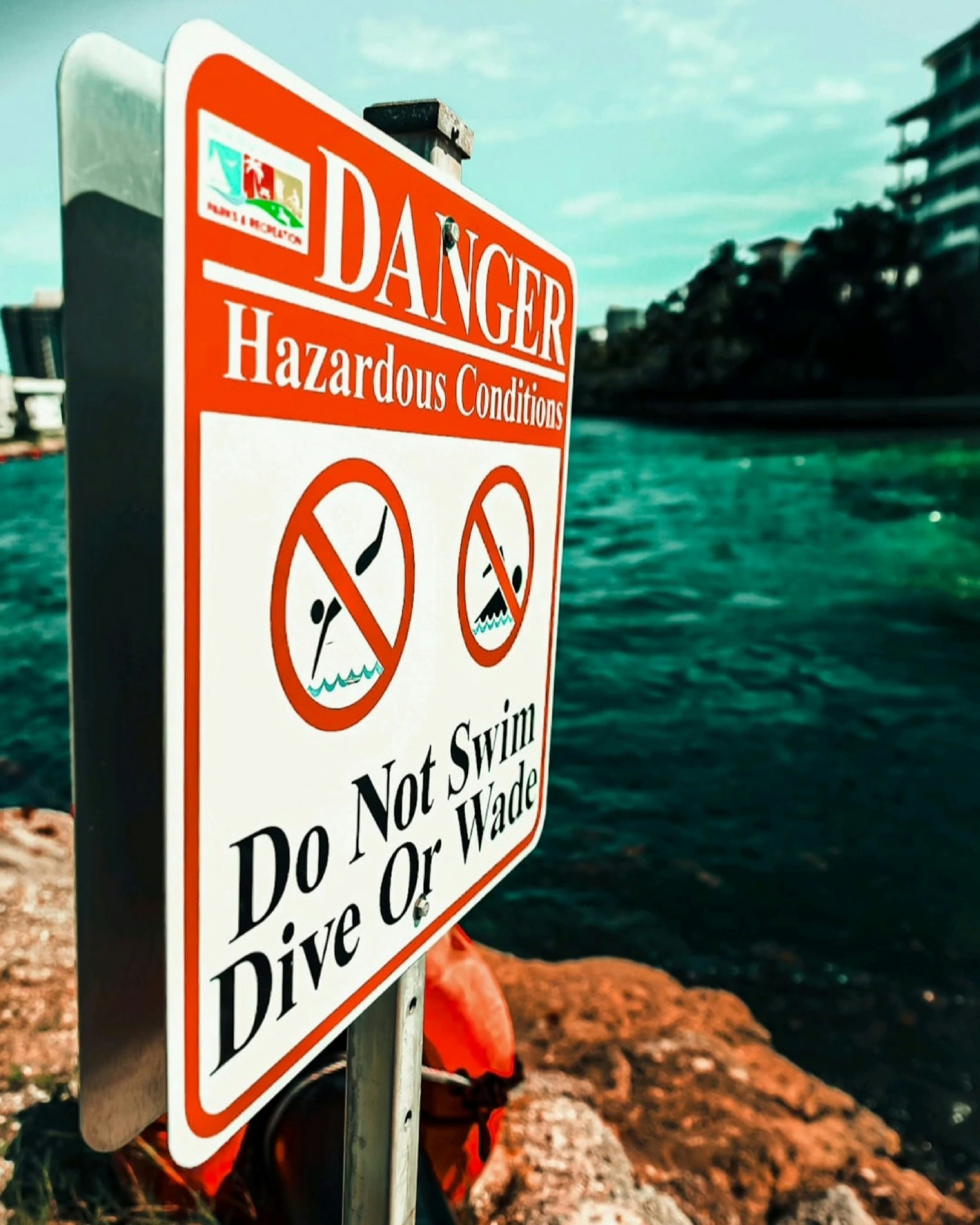 A red and white sign reading “Danger: Do Not Swim, Dive or Wade” near water—symbolizing emotional boundaries in trauma healing with EMDR.