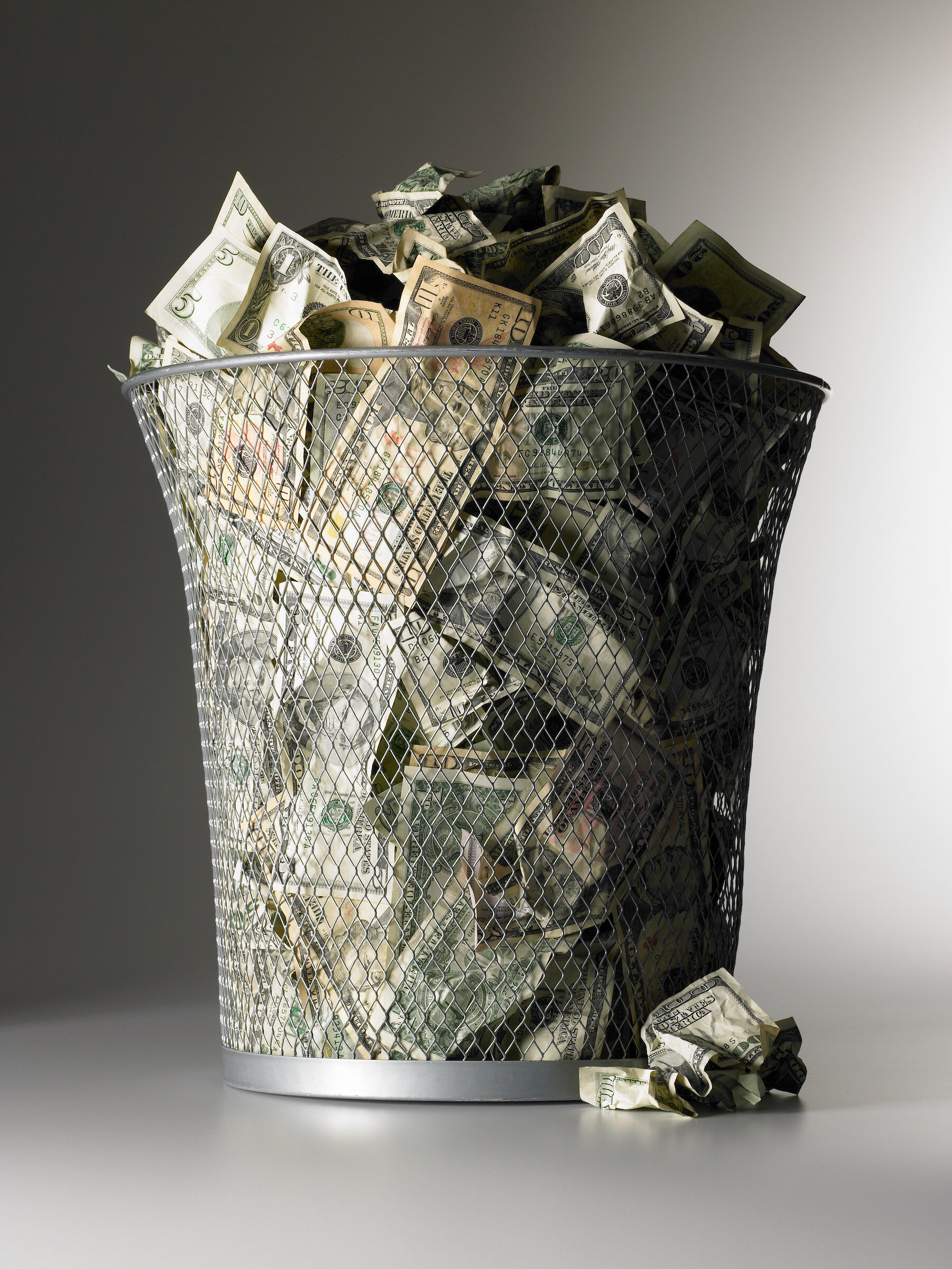 Money in trash bin throwing money away.jpg