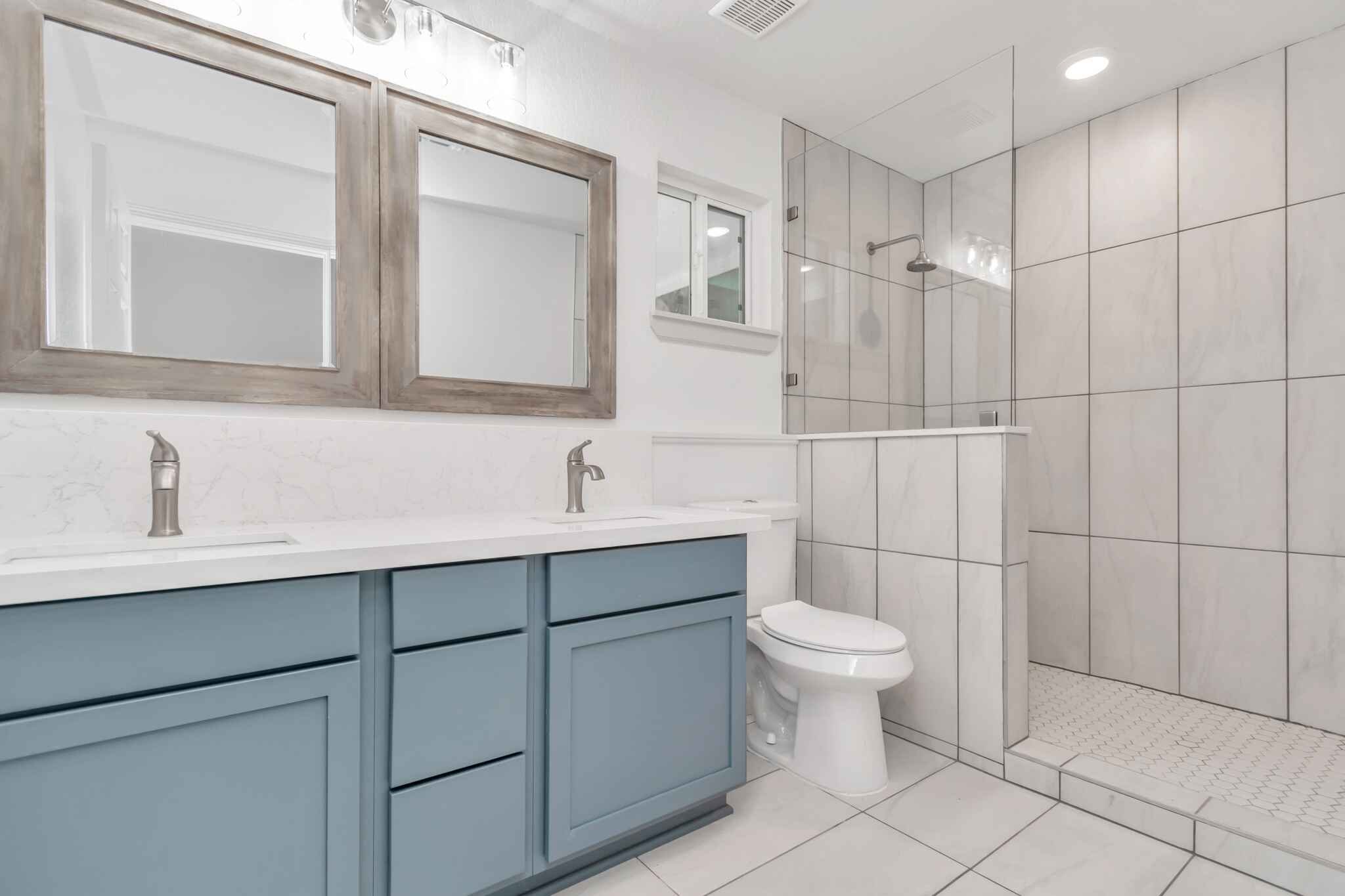 Primary bathroom featuring blue cabinetry and a walk-in-shower.