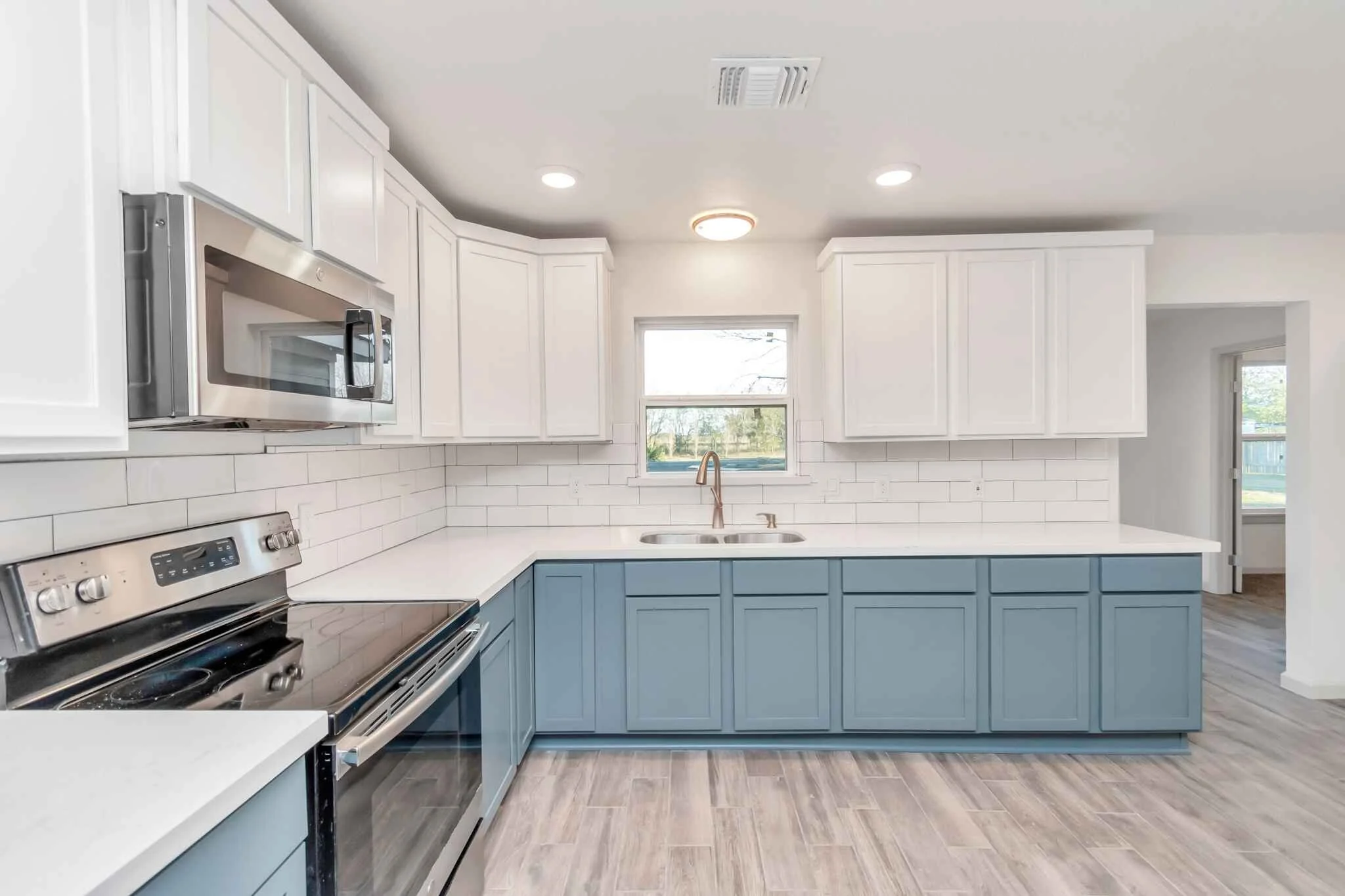 Blue and white kitchen with an electric stove-top, microwave, and sink.
