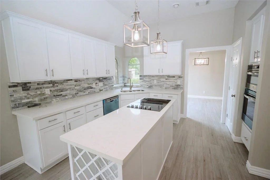 Modern white cabinet kitchen with a wine rack, stove-top island.