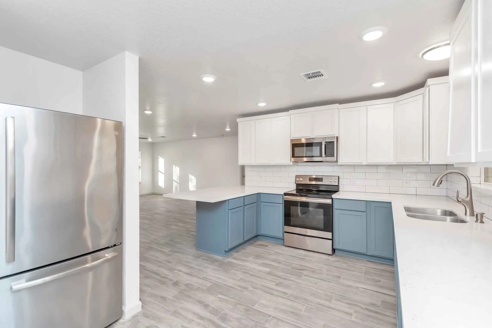 Kitchen view angled to living room with appliances.