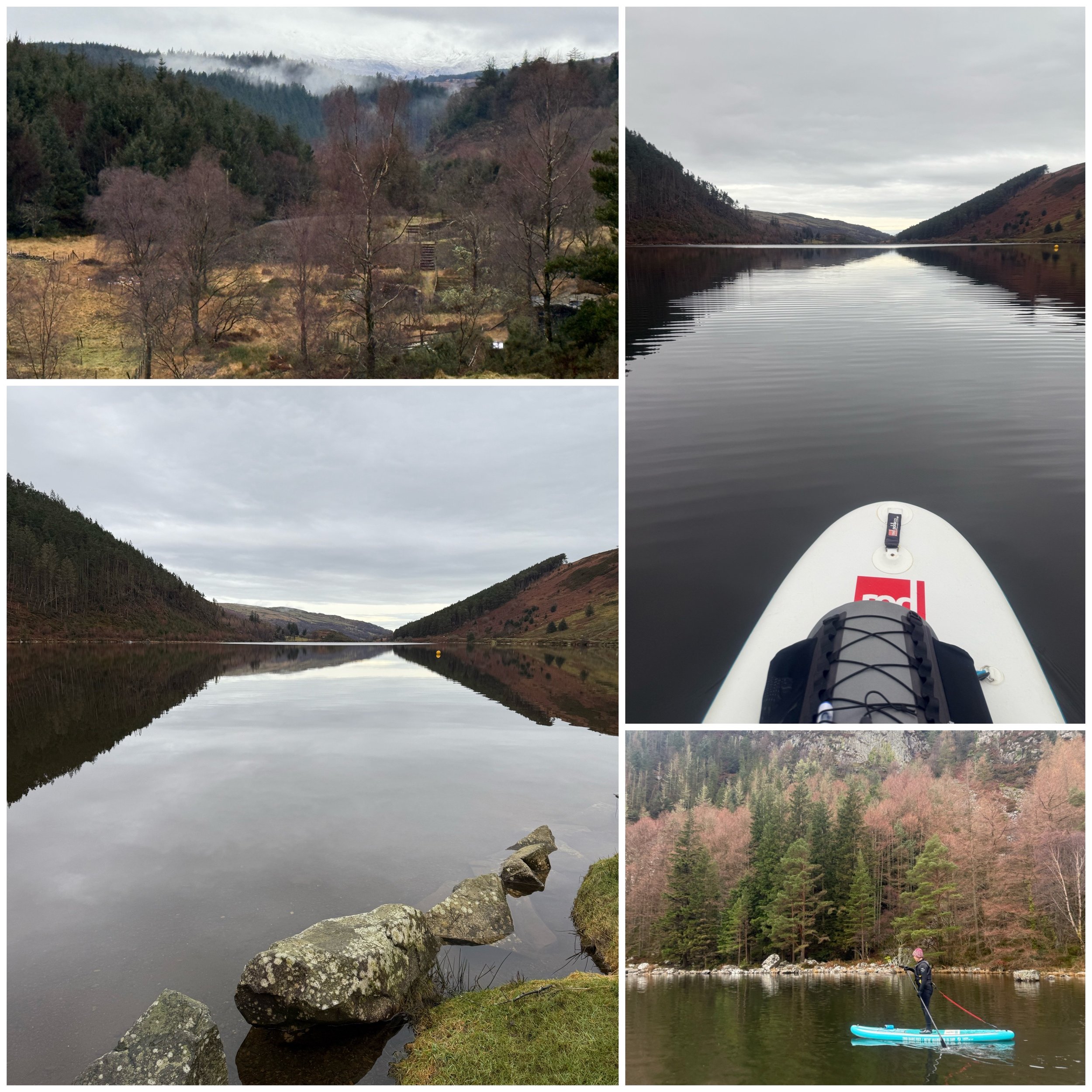 Scenic lakeside view with moody cloudy sky, forested hills, a paddleboarder on calm water, and rocks along the shoreline.