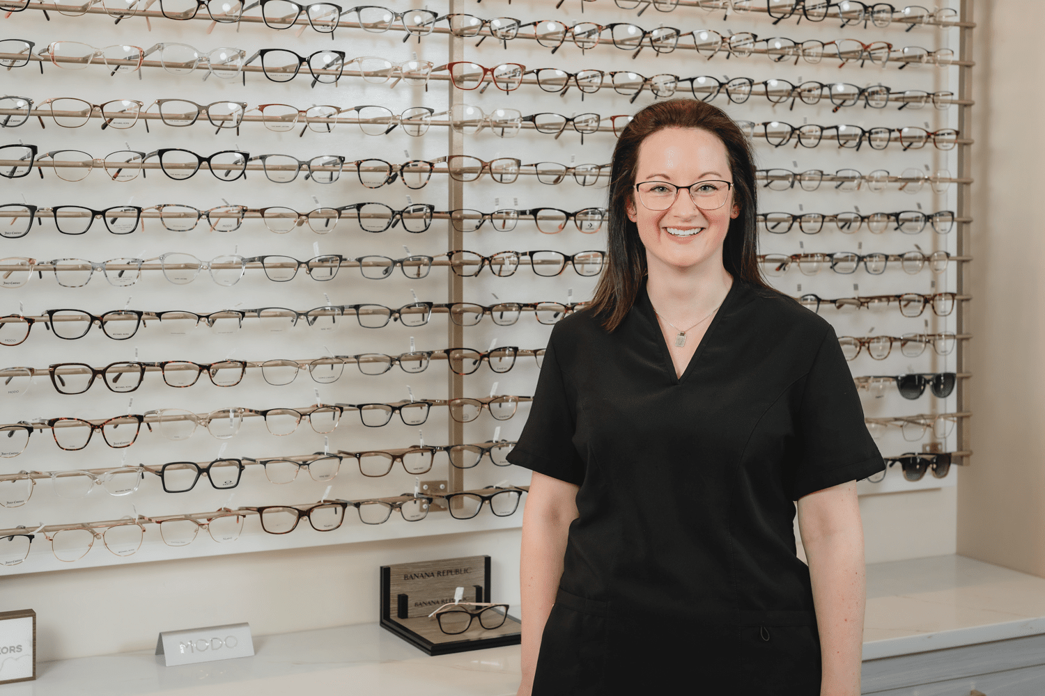 Our medical office administrator Ashley standing in front of the womens frame rack smiling for the photo