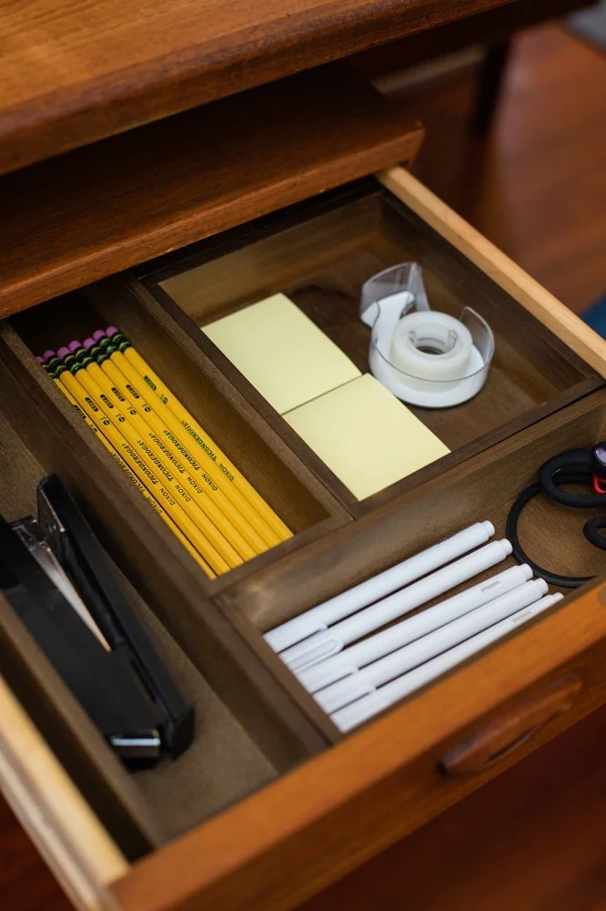 Well-organized office drawer with dividers containing pencils, pens, Post-its, tape, a stapler, and other office essentials. 