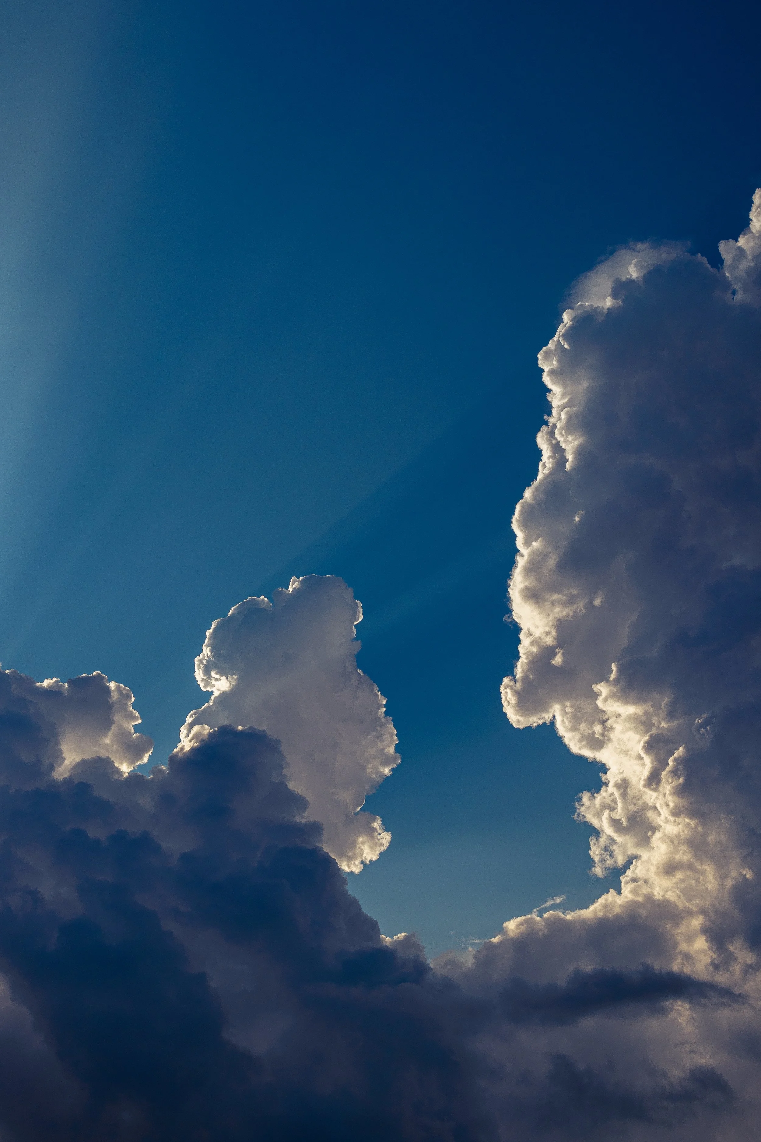 Cloudy sky with large white clouds and a clear blue background.