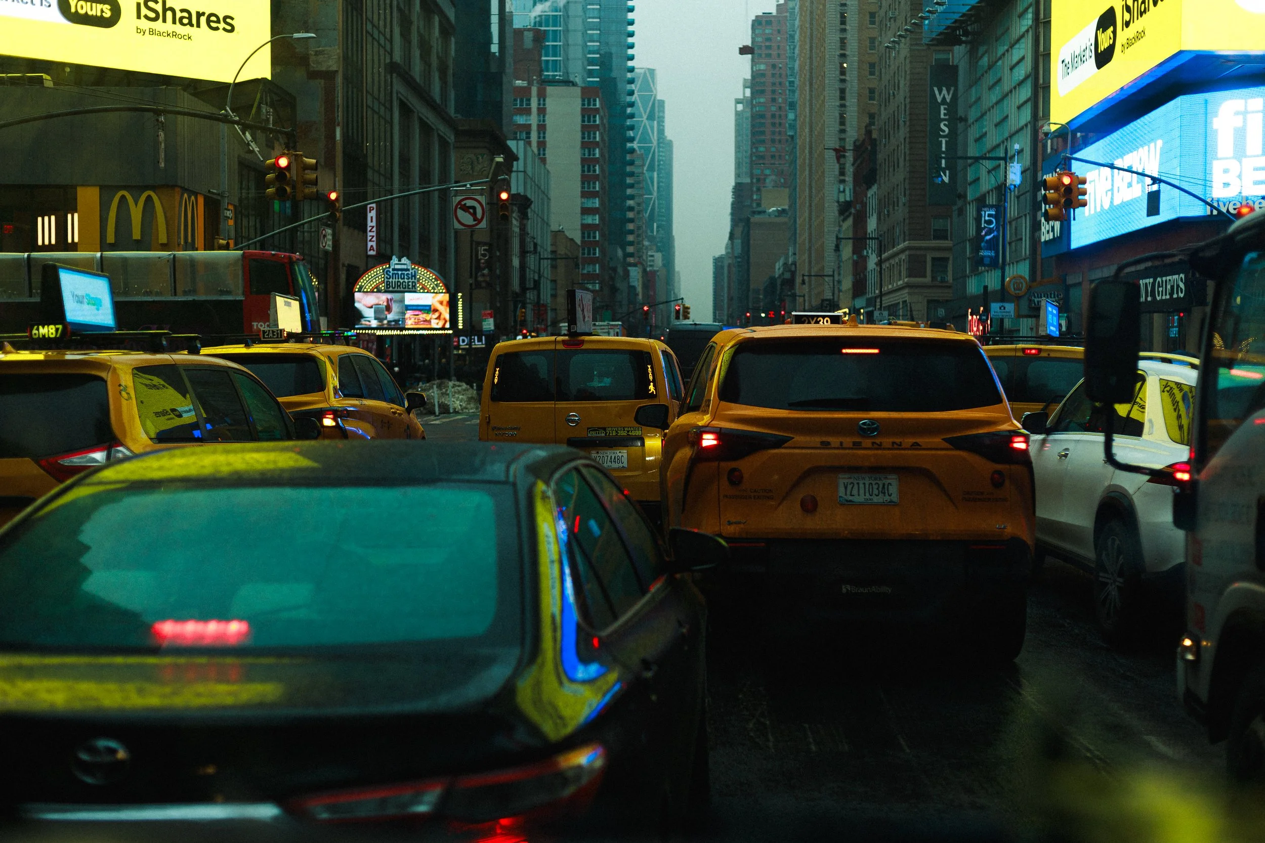 Nighttime city street with yellow taxis, traffic lights, and illuminated billboards in Times Square, New York City.