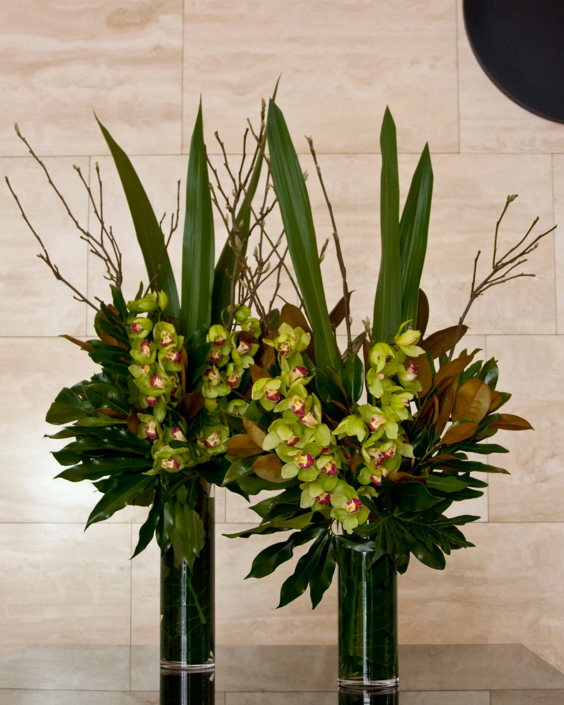 Foyer Flowers for Melbourne Corporate Organisations. Featuring green cymbidium orchids, gymea leaves, magnolia foliage and aurellia leaves with magnolia sticks. Botanic Flowers 1300 820 920. 