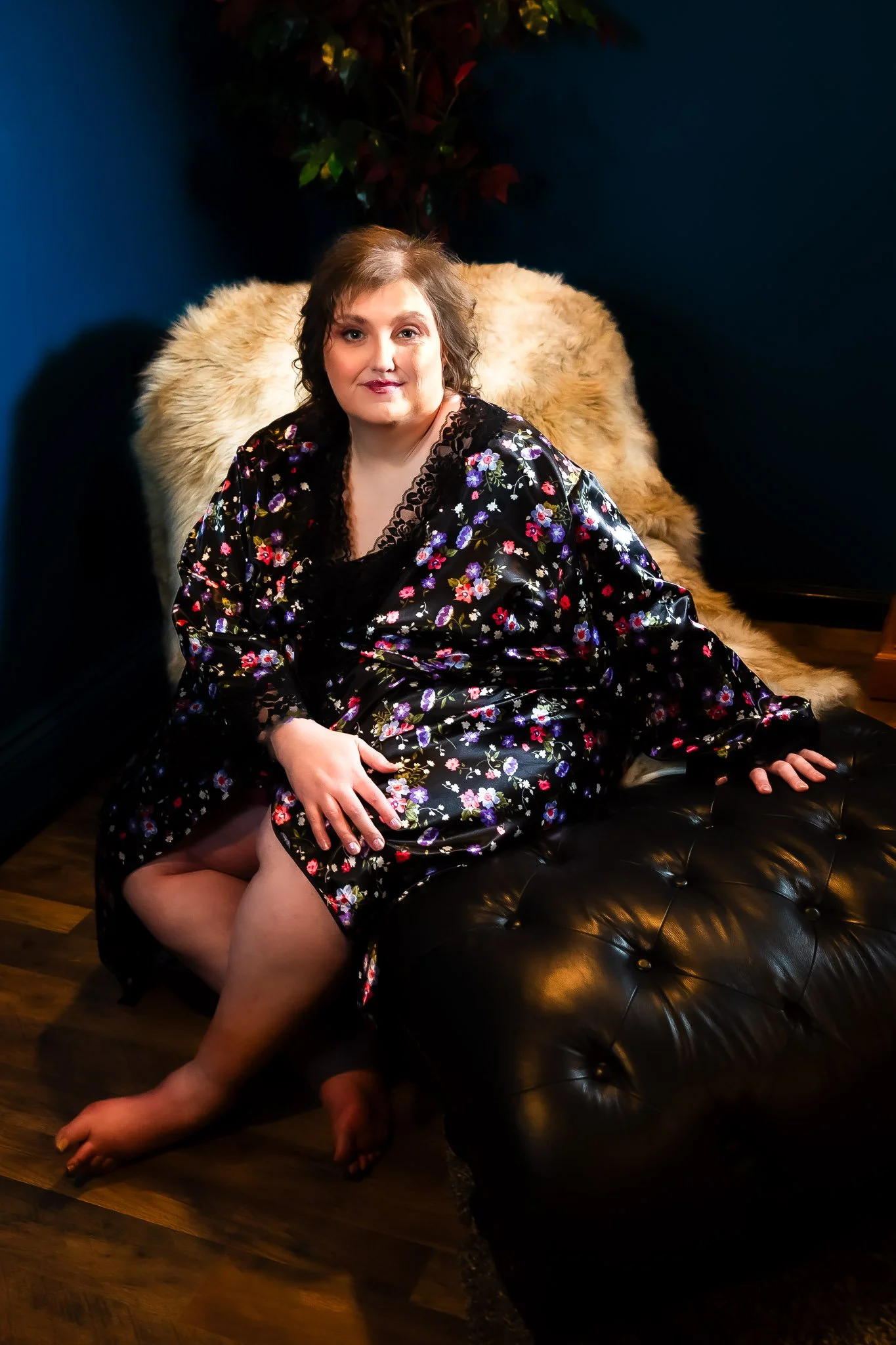Curvy woman in a sheer floral robe seated on a fur-draped chair during a plus-size boudoir session in Bangor, Maine
