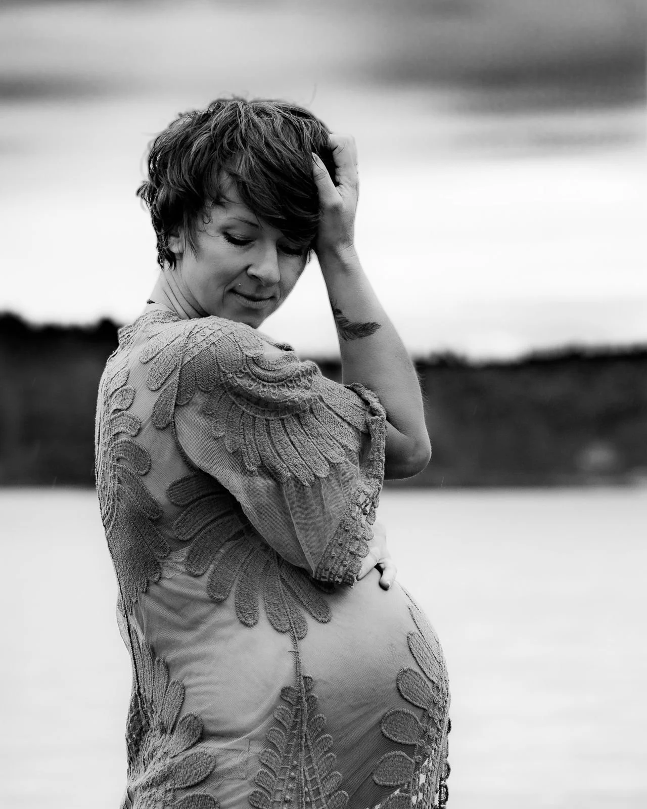 Expecting mother in lace for a maternity boudoir portrait by the water in Maine