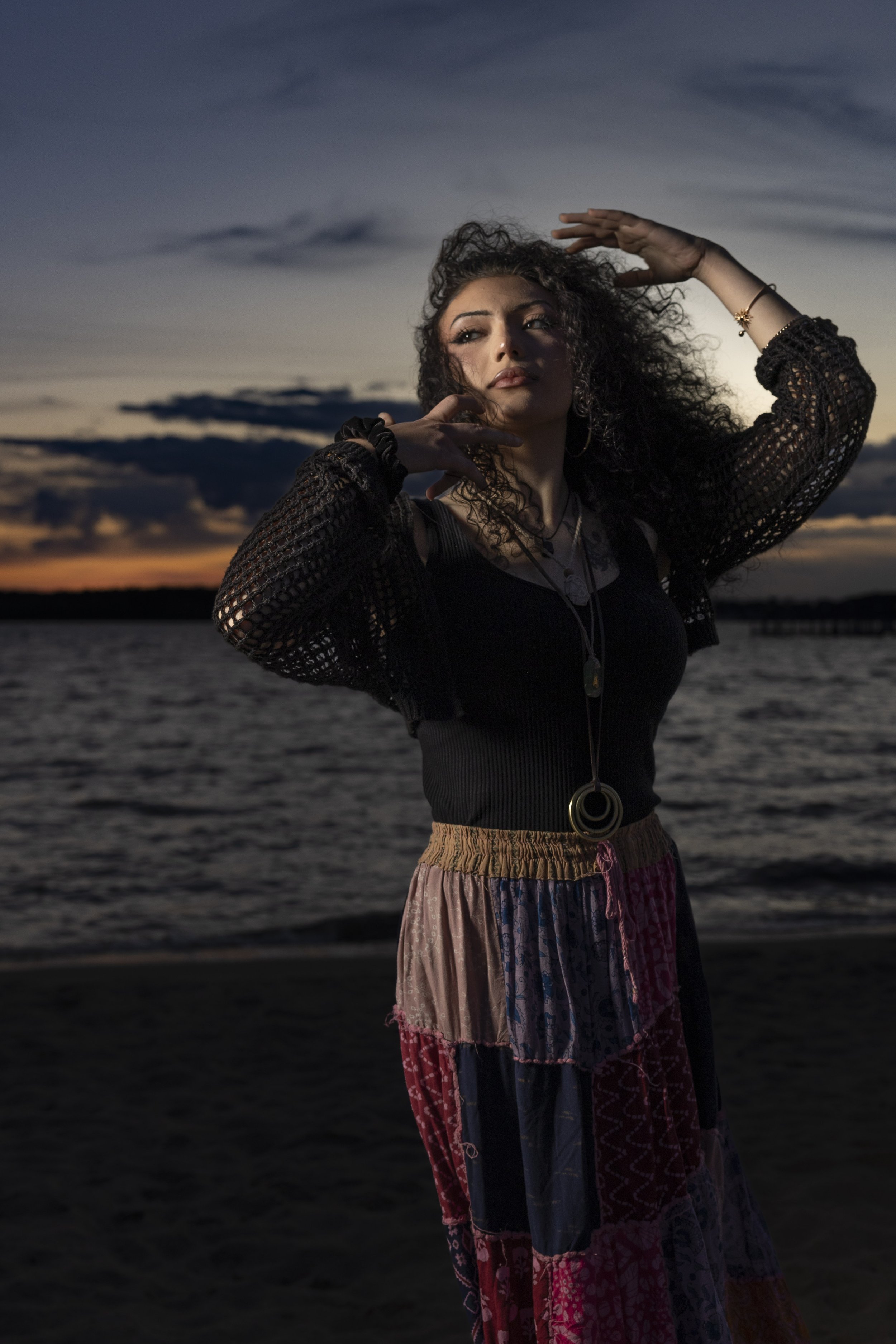 Woman in a lace top and patterned skirt on a Maine beach at sunset