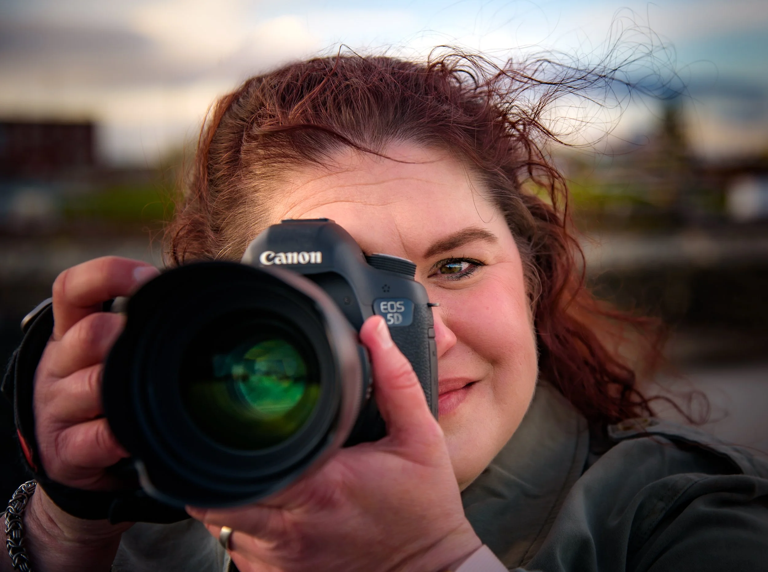 Jen Jackson, boudoir photographer and owner of T3 Portraits in Maine, smiling behind her camera outdoors