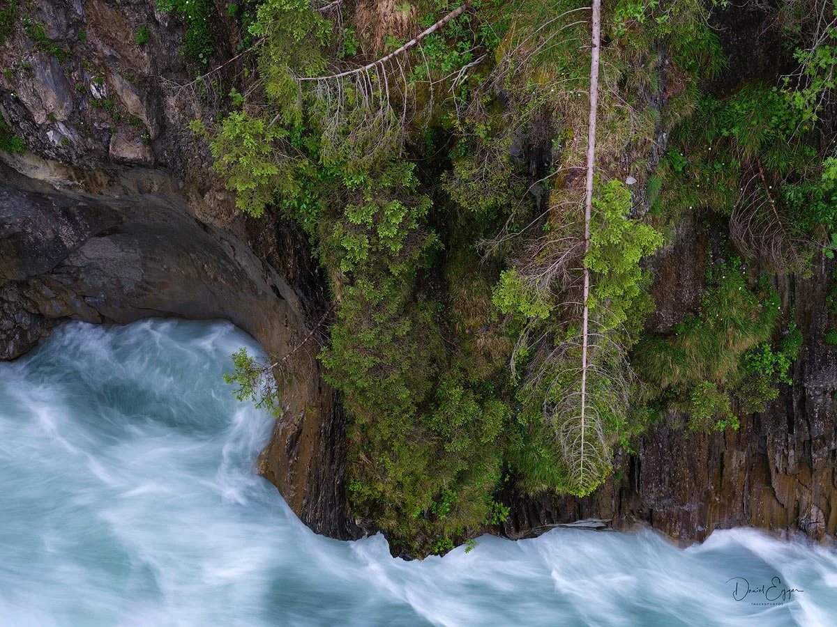 Vogelperspektive auf einen Fluss, der durch eine felsige, bewaldete Schlucht fließt.