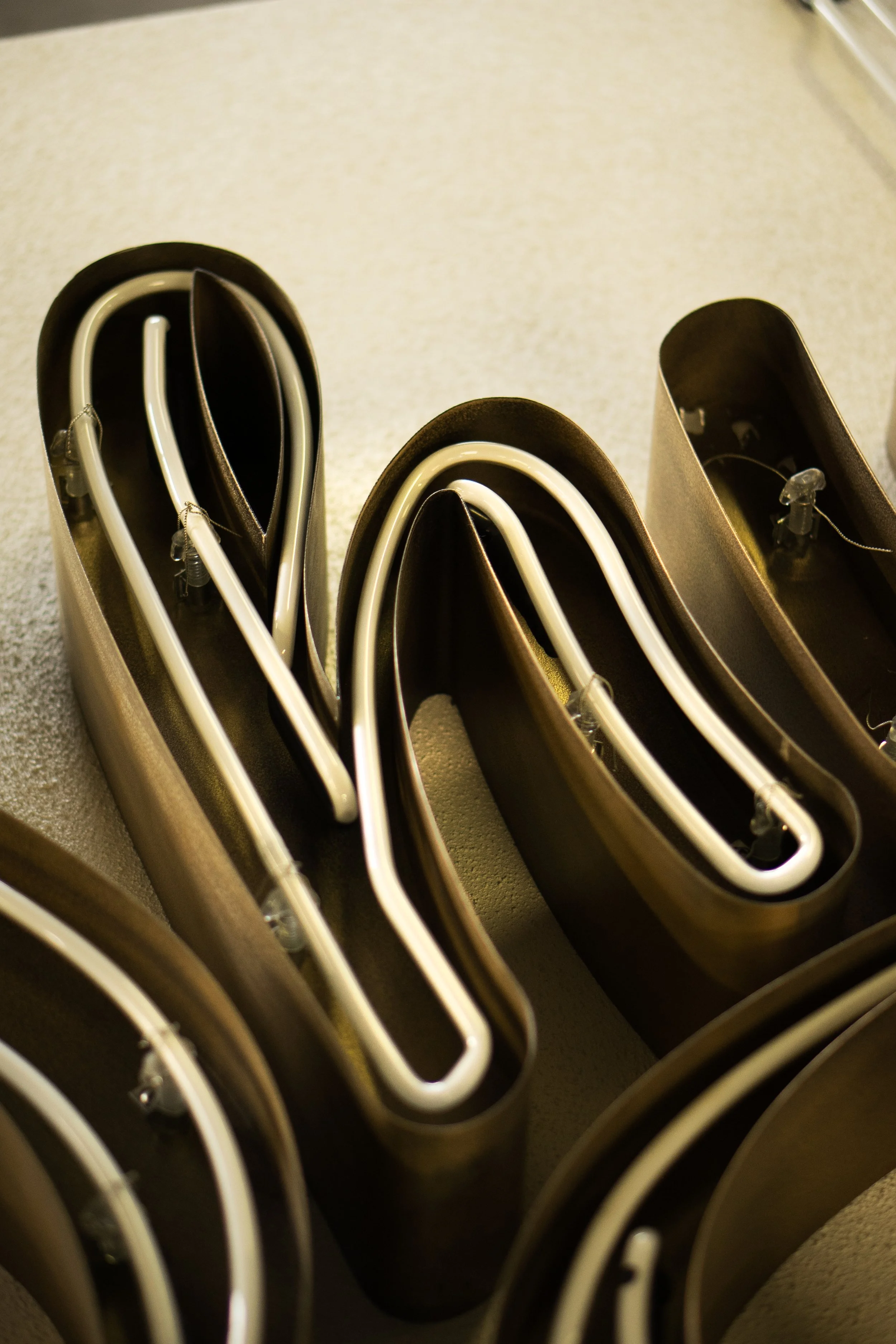 Neon light tubing unrolled and stored in black boxes, placed on a beige surface.