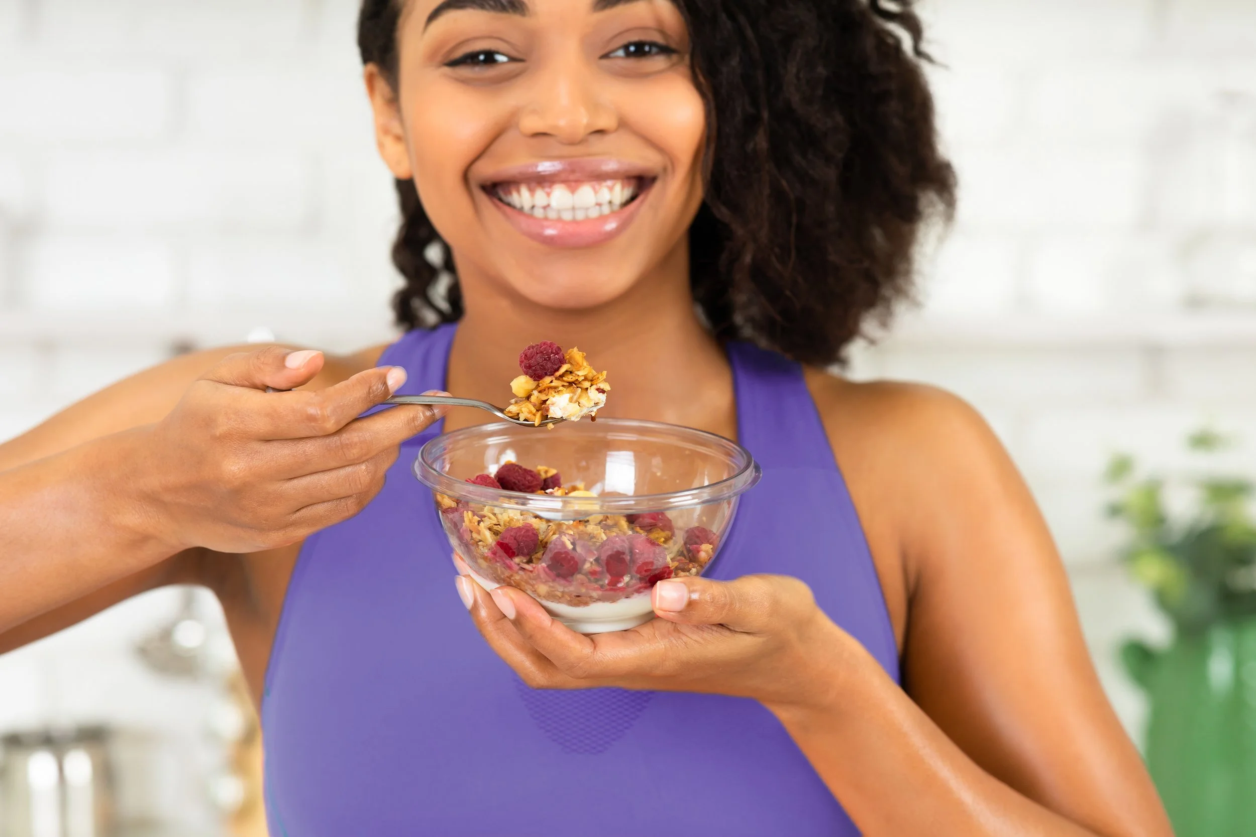 A smiling woman enjoying a healthy, sugar-free meal from Provenance Aesthetic & Wellness's weight loss program in Missouri City.