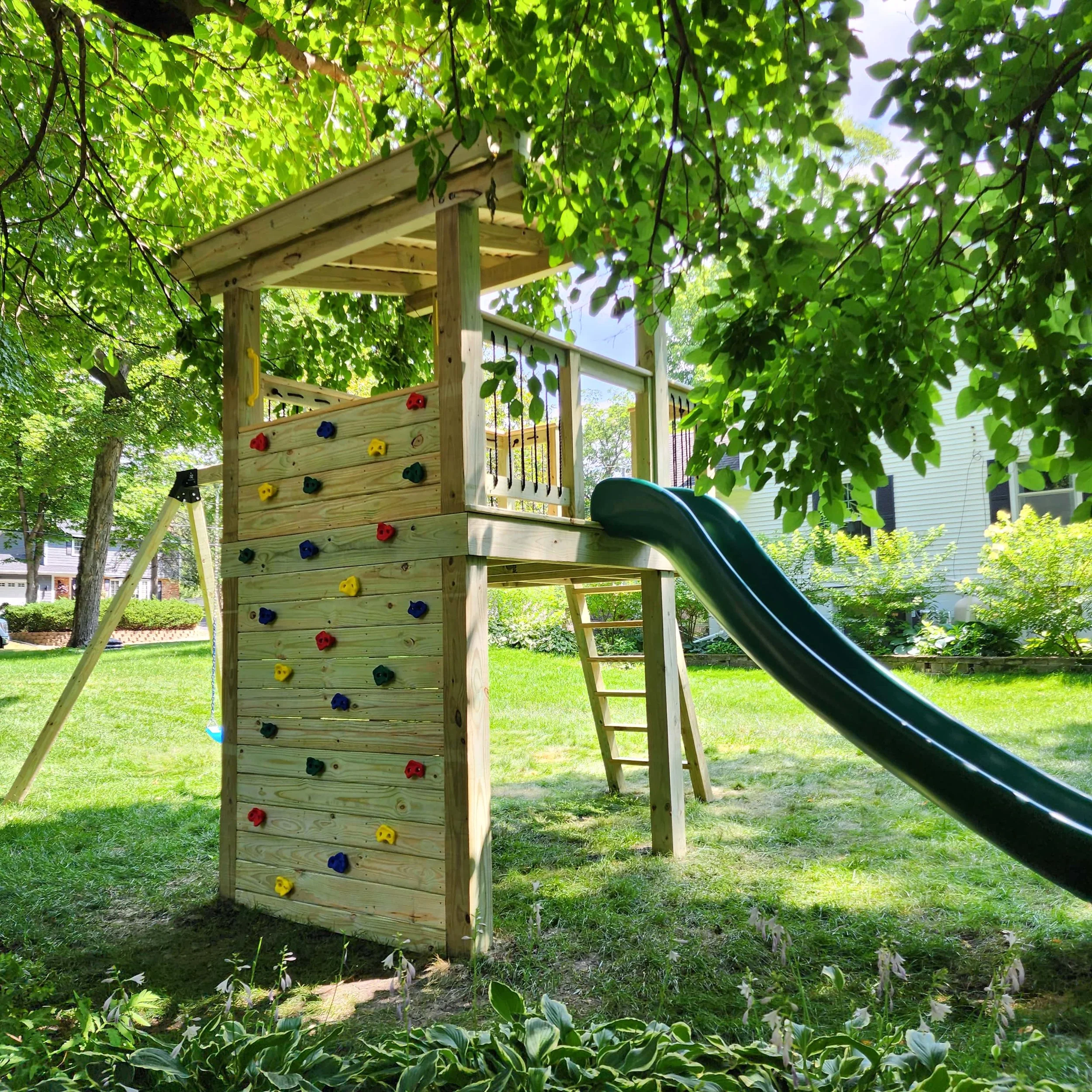 custom backyard swing set rock wall and green swoop slide