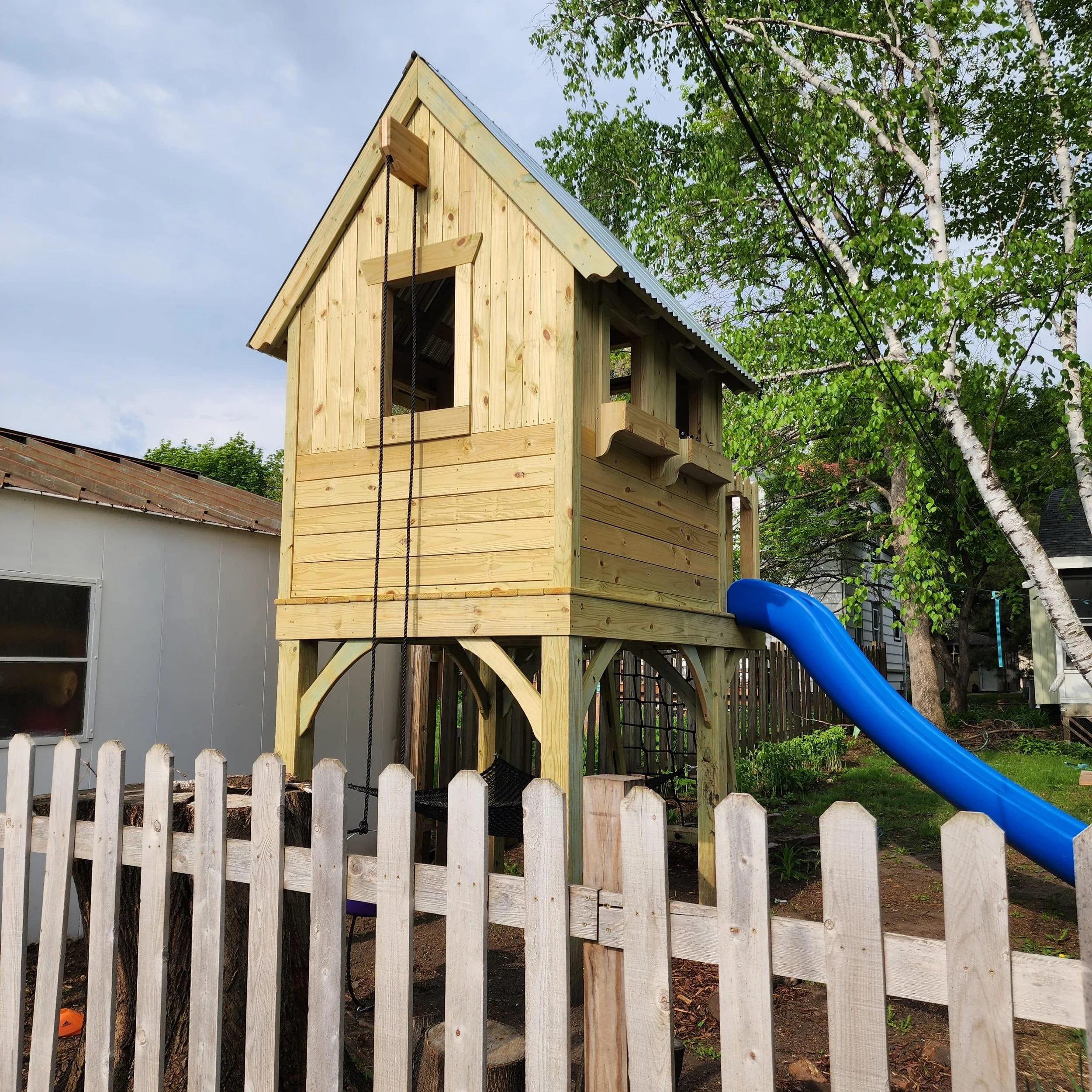 custom cottage play structure behind picket fence