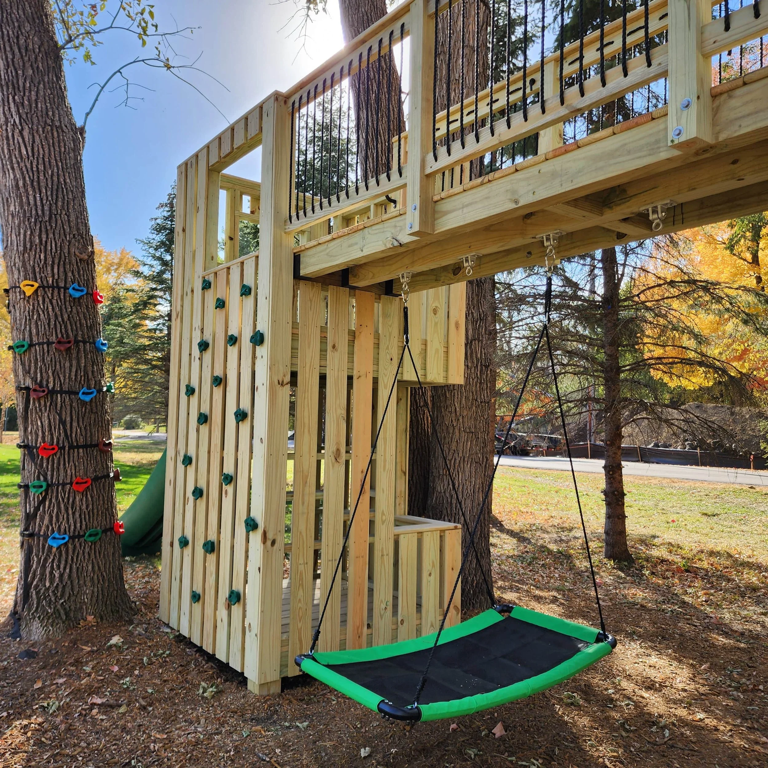 custom tree fort climbing wall and bridge with platform swing