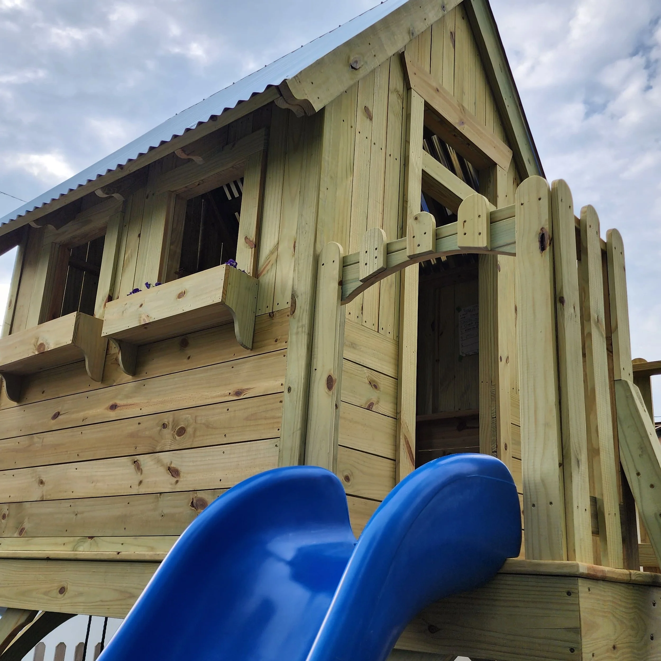 custom play structure with blue slide and arched top railing