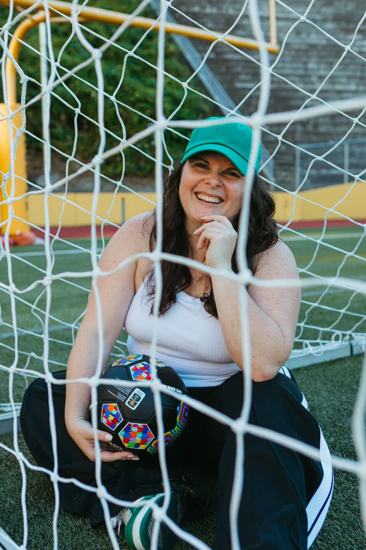 Ellyn sitting in a soccer goal holding a ball
