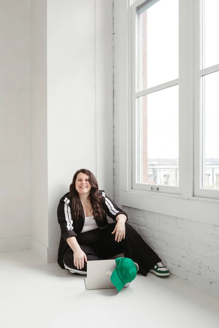 Ellyn sitting on the studio floor with her laptop, laughing