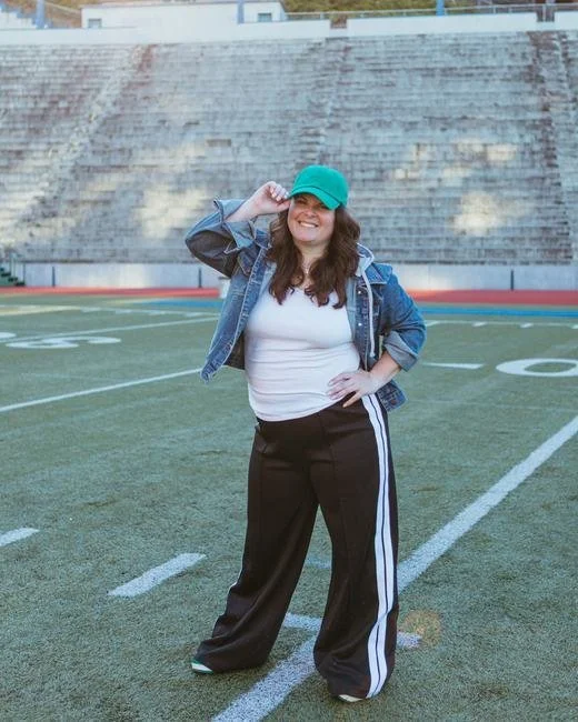Ellyn standing on the football field in a green cap