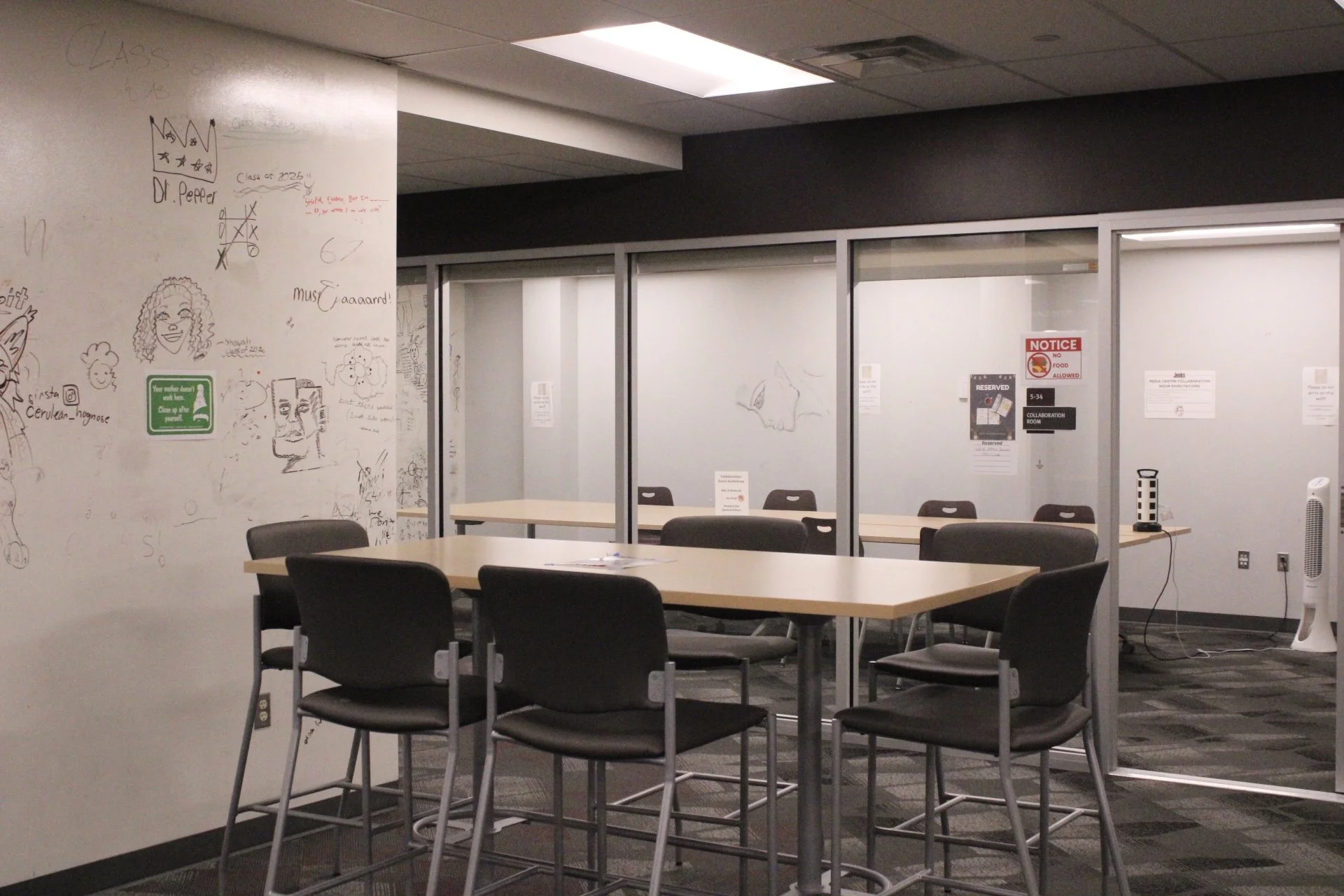 High-top table with 6 chairs around it sits in the library.