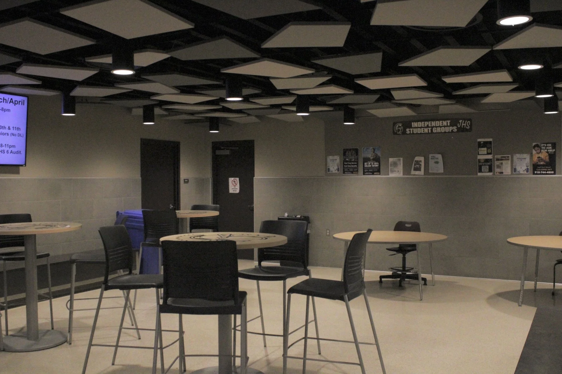 Tall tables with four chairs around them in a common space.