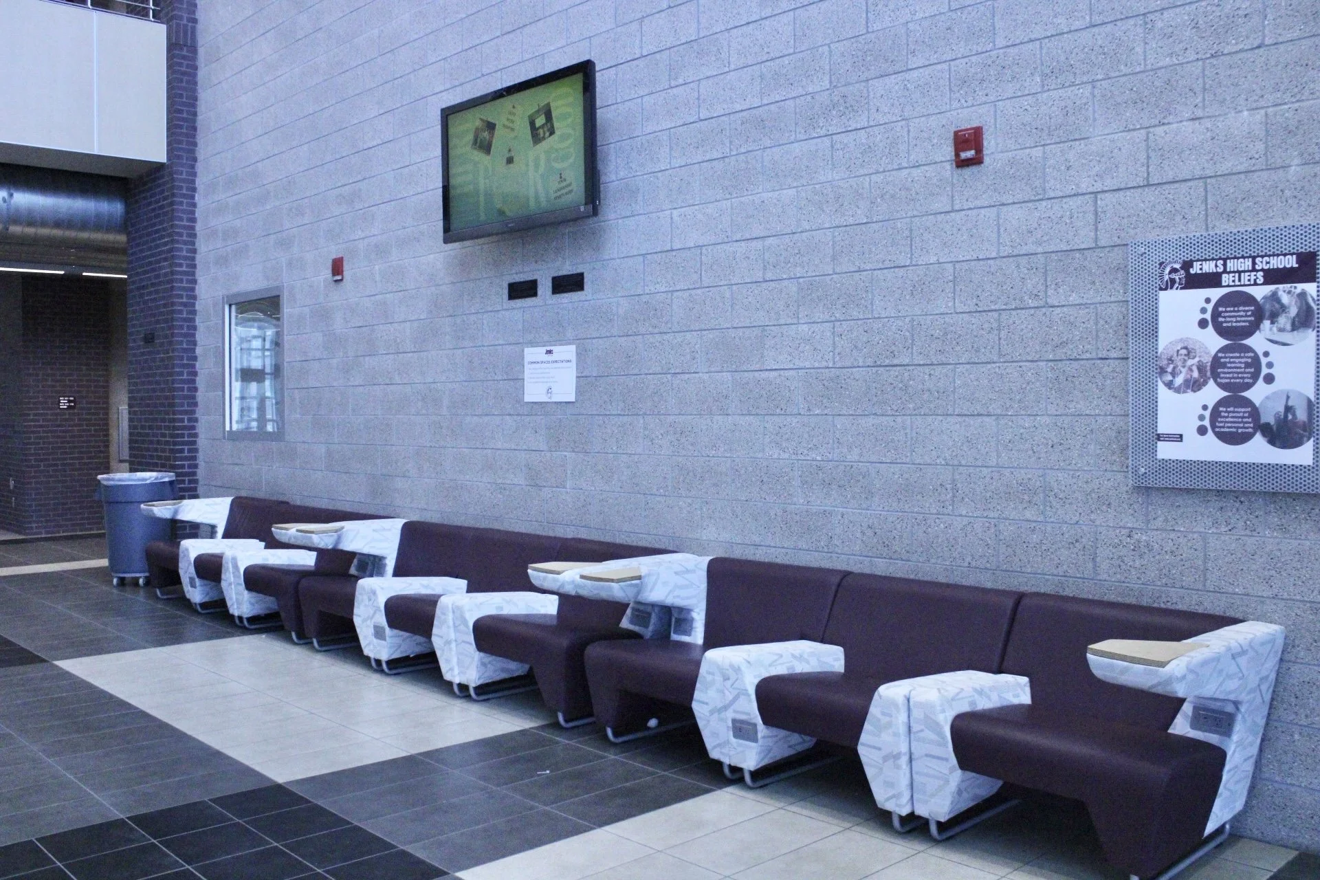 Long row of chairs with built in desks along a wall.