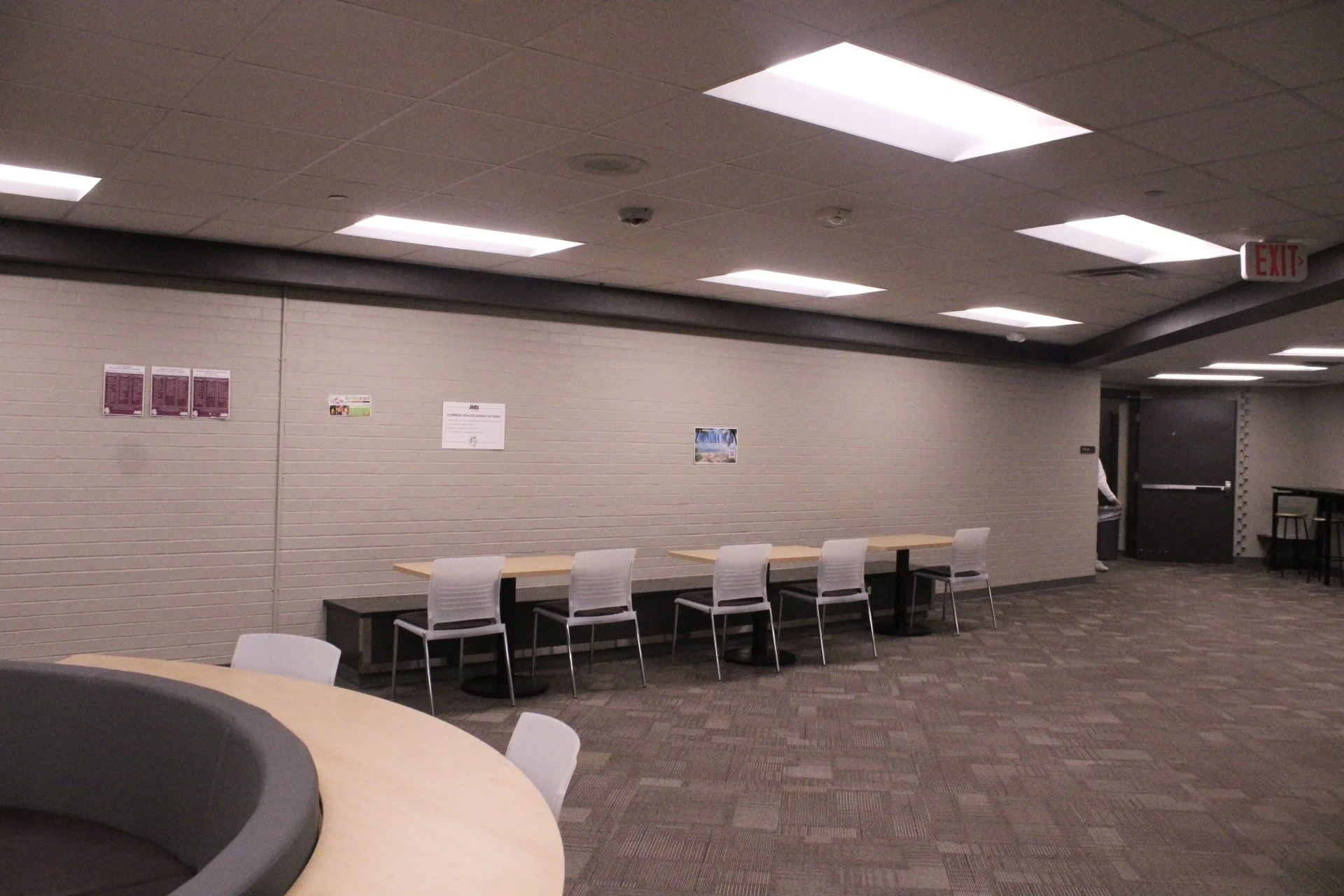Tables situated along a wall with a long bench for seating on one side and chairs on the other.