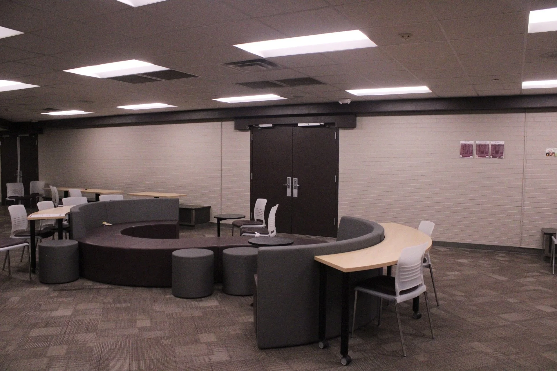 Curved couches and tables with chairs sit in the middle of a common space.