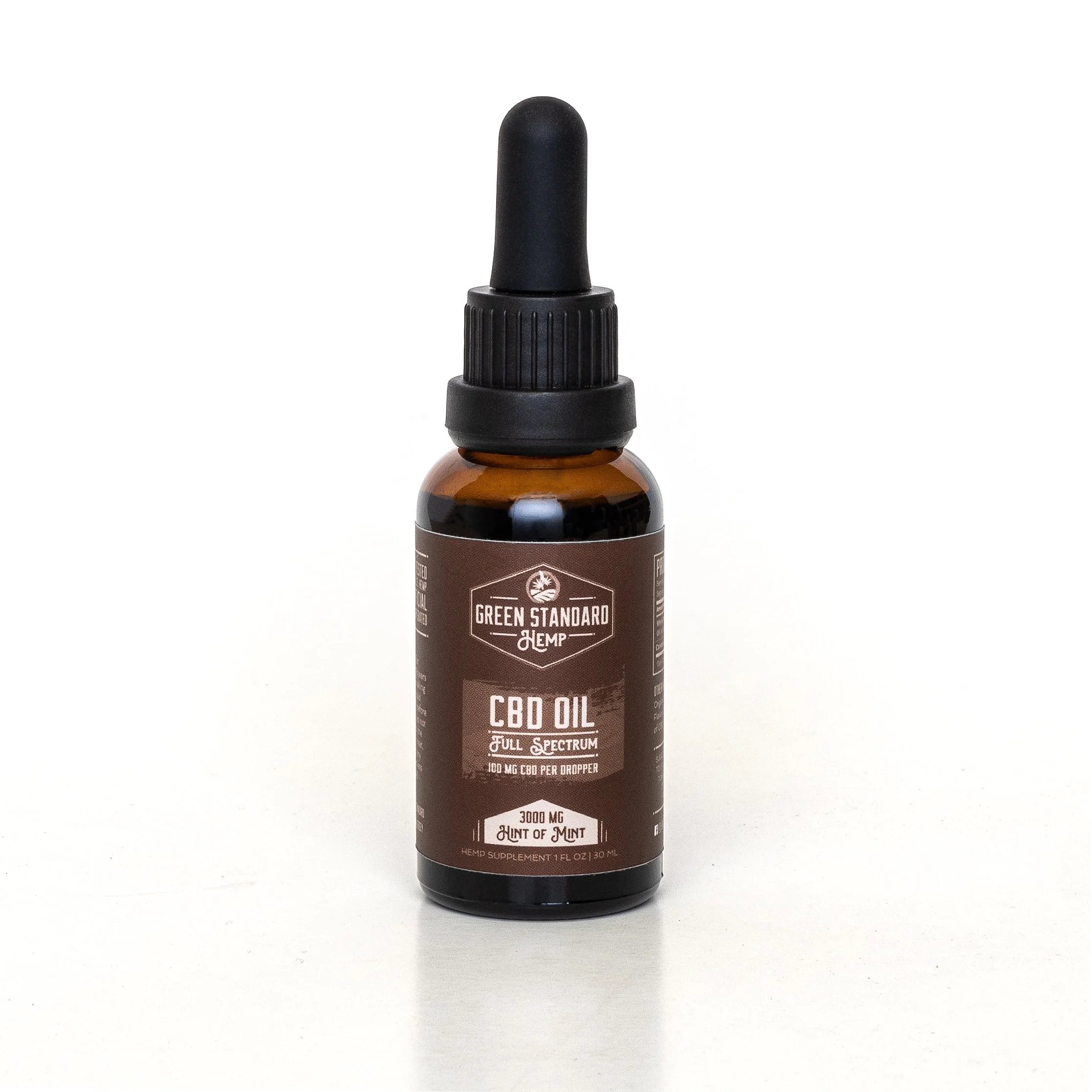 Small amber glass bottle with black dropper cap labeled 'Green Standard Hemp CBD Oil Full Spectrum 100mg CBD per dropper, 3000mg, Hint of Mint'.