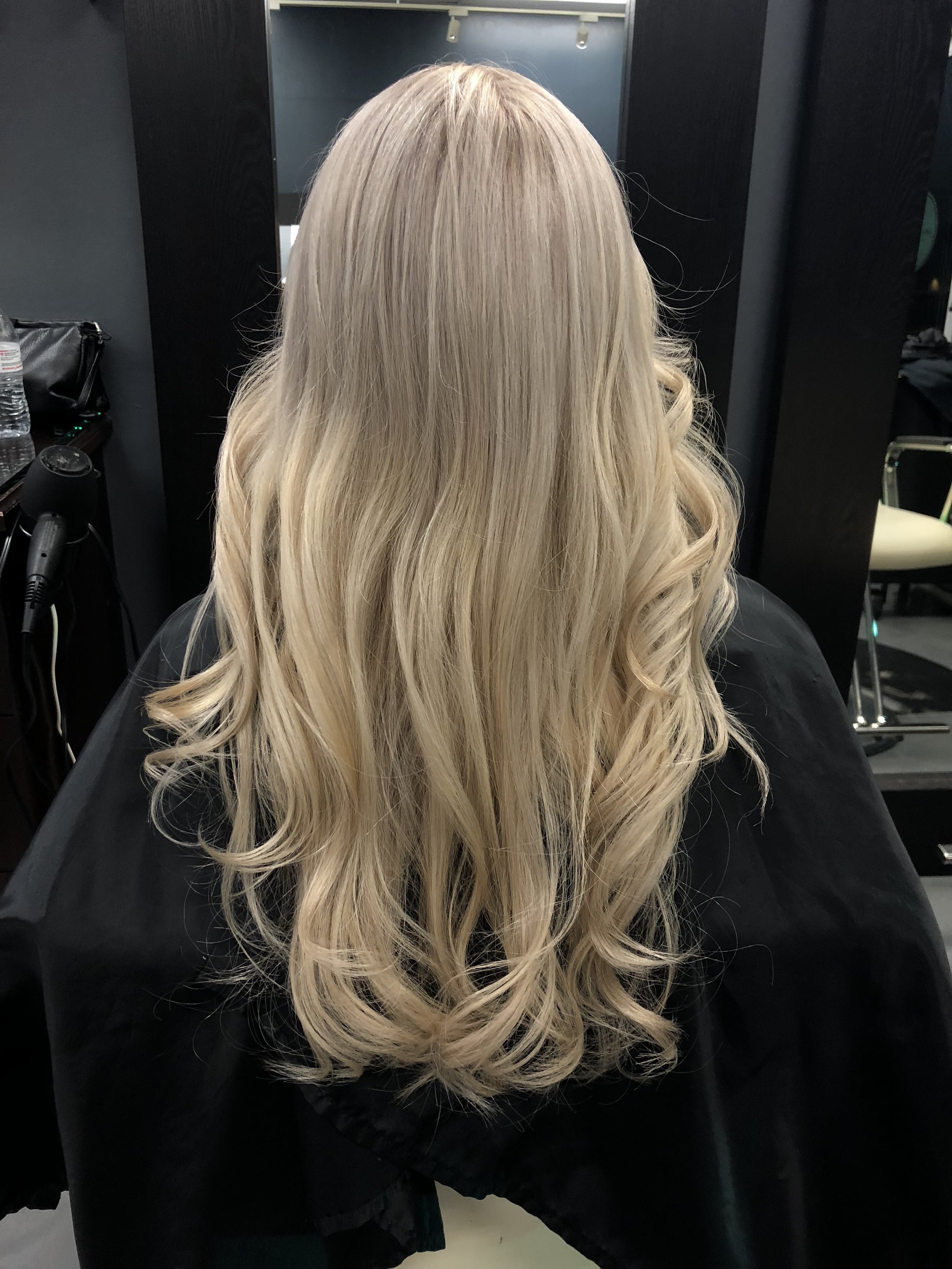 Blonde wavy hair from the back in a salon setting.