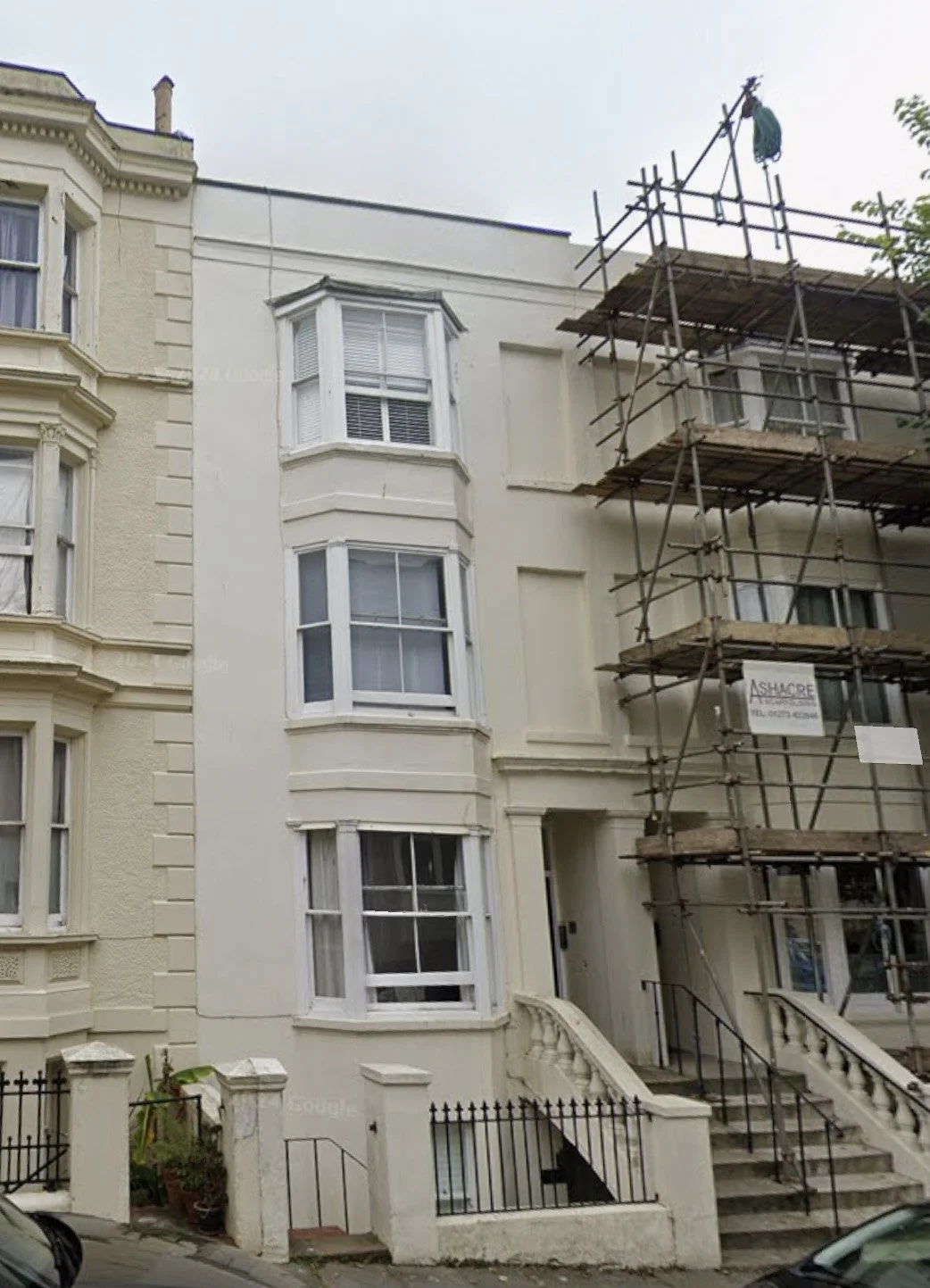 White facade of a terraced building with 3 floors with sash windows