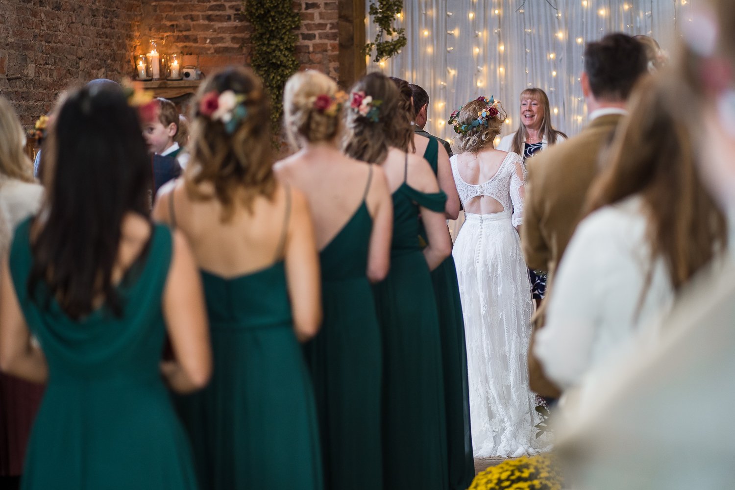 Bridesmaids walk down aisle at rustic barn wedding
