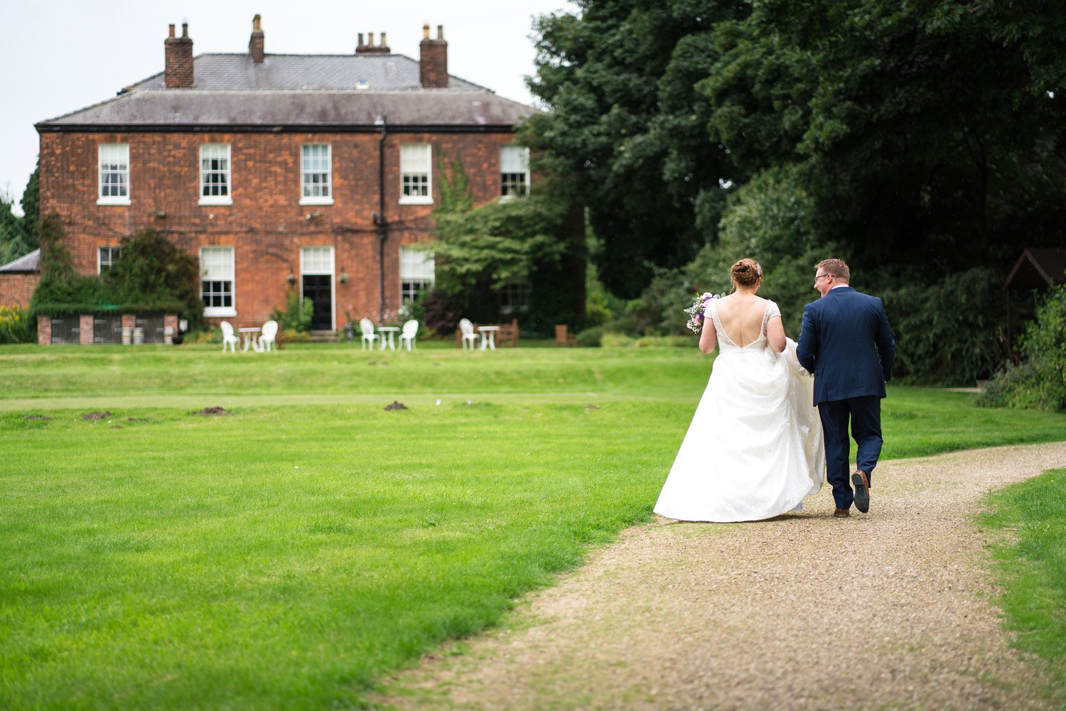 Bride and groom walk in grounds of Rowley Manor Hotel