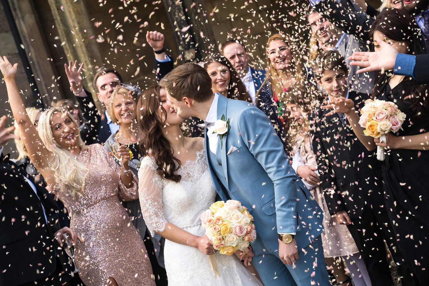 Bride and groom kiss with confetti at Ripley Castle in Harrogate