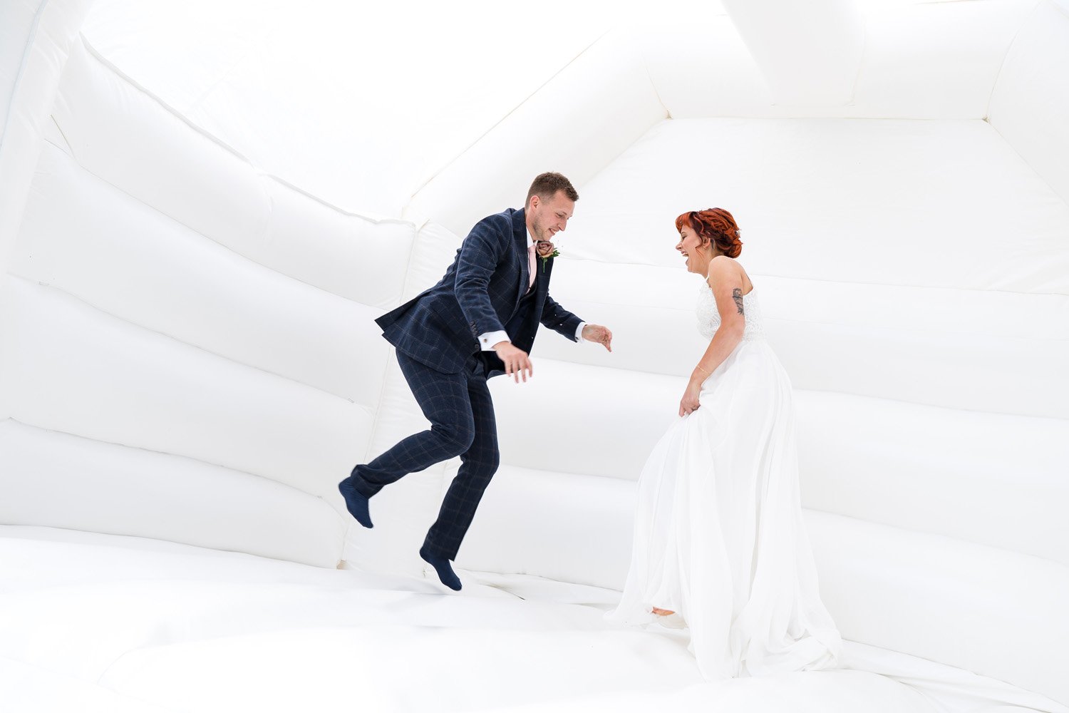 Bride and groom jump on white bouncy castle at Dunedin Country House