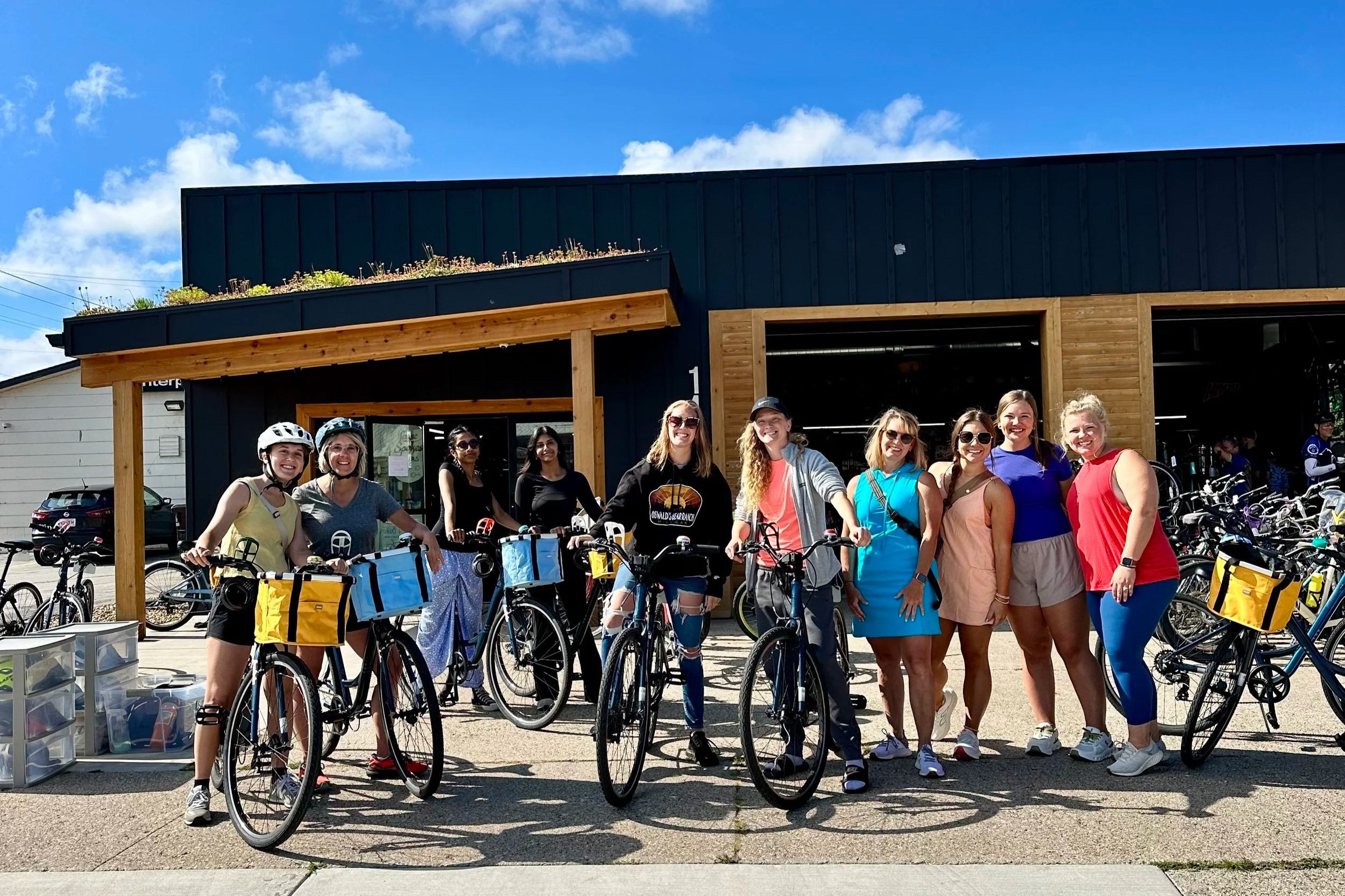 Group of people stand outside of bike shop with rental bikes